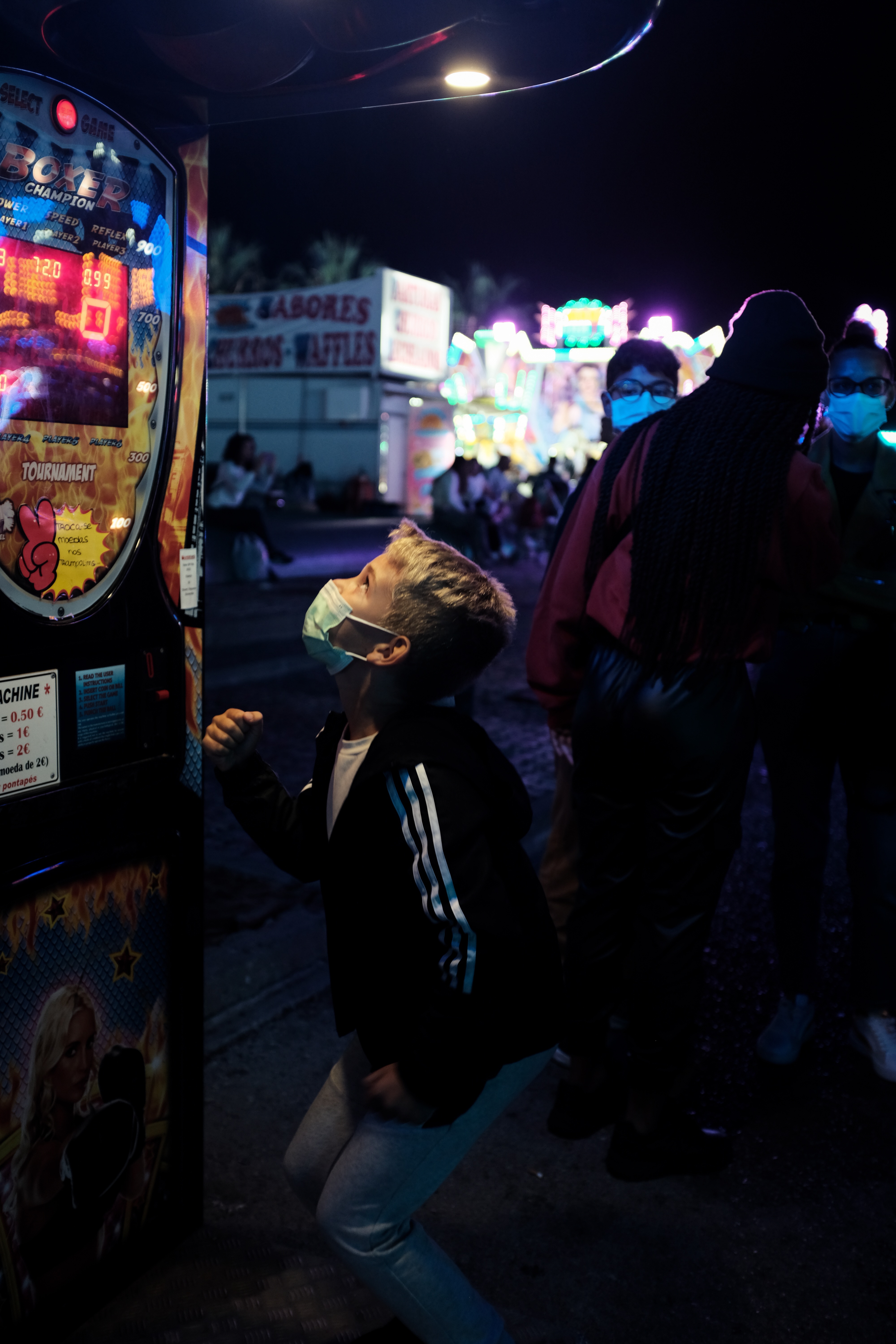 Boy jumping up to reach a button on a fairground arcade game.