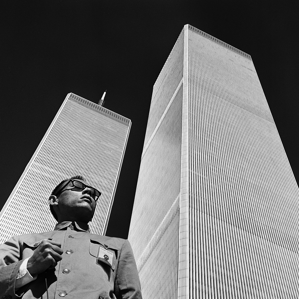 a man in a Zhongshan suit stands in front of the twin towers