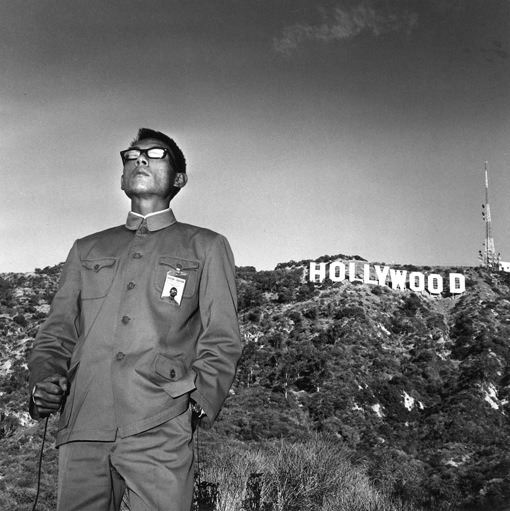 a man in a Zhongshan suit stood in front of the hollywood sign