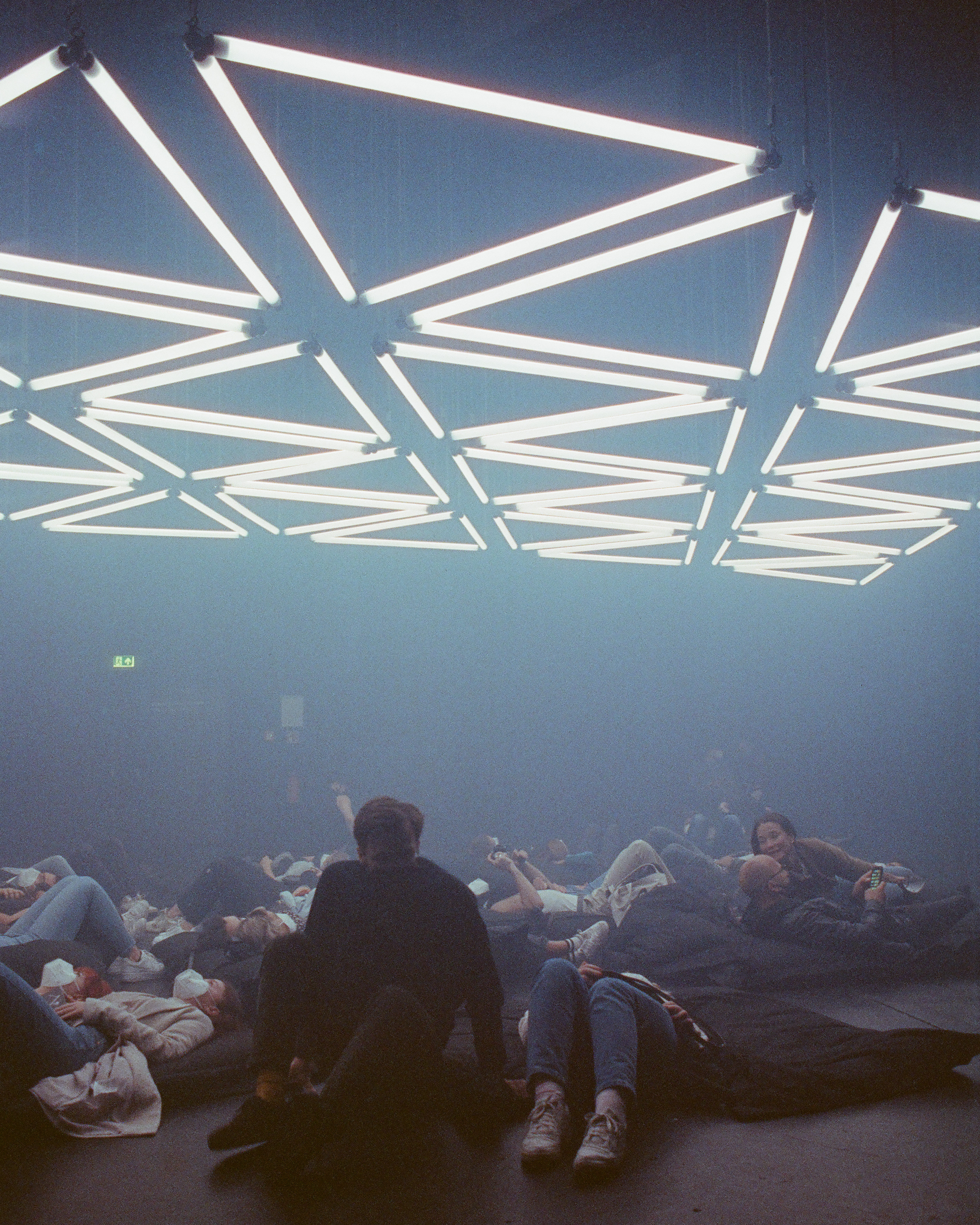 People lie on the ground under a light up display