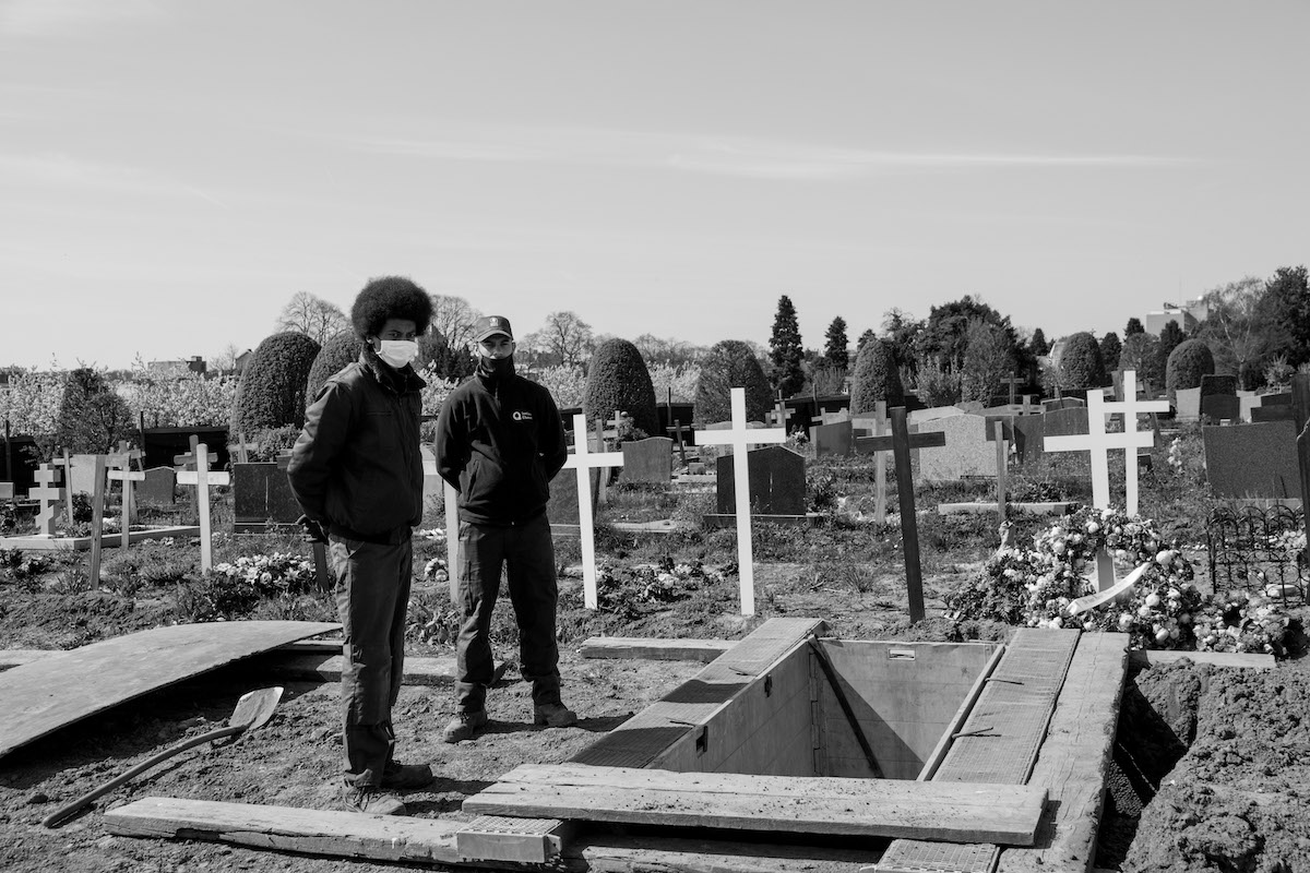 Jacques Vermeer, Patrick, cemetery - Black and white photo of two men posing with their hands behind their backs in front of an open grave