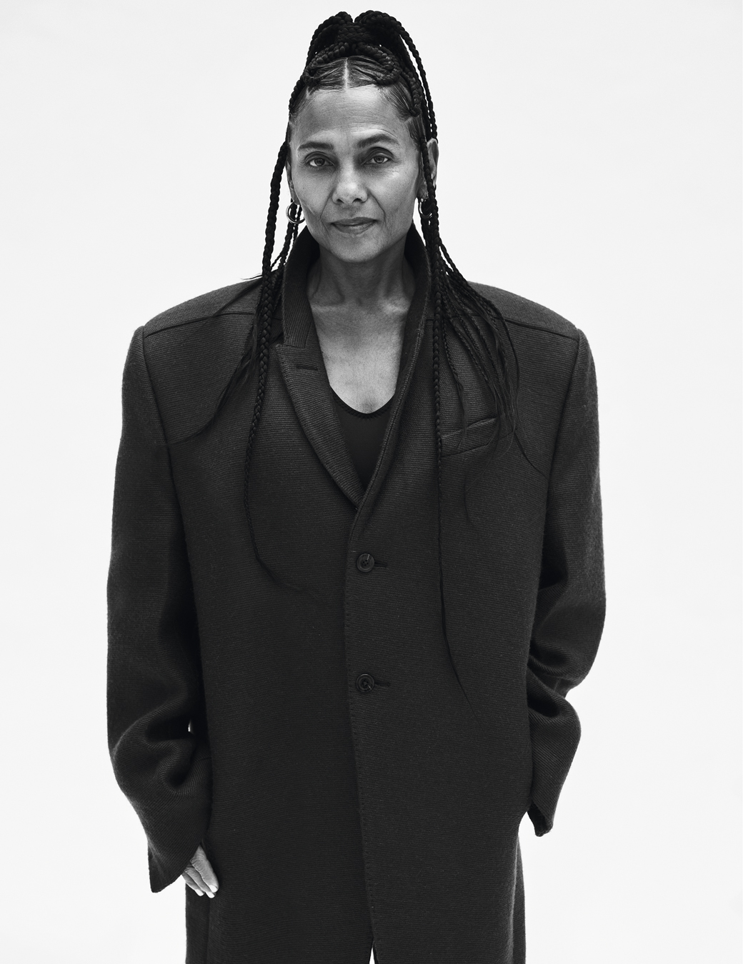 Portrait of Ming Smith wearing a black trench coat and hoop earrings.