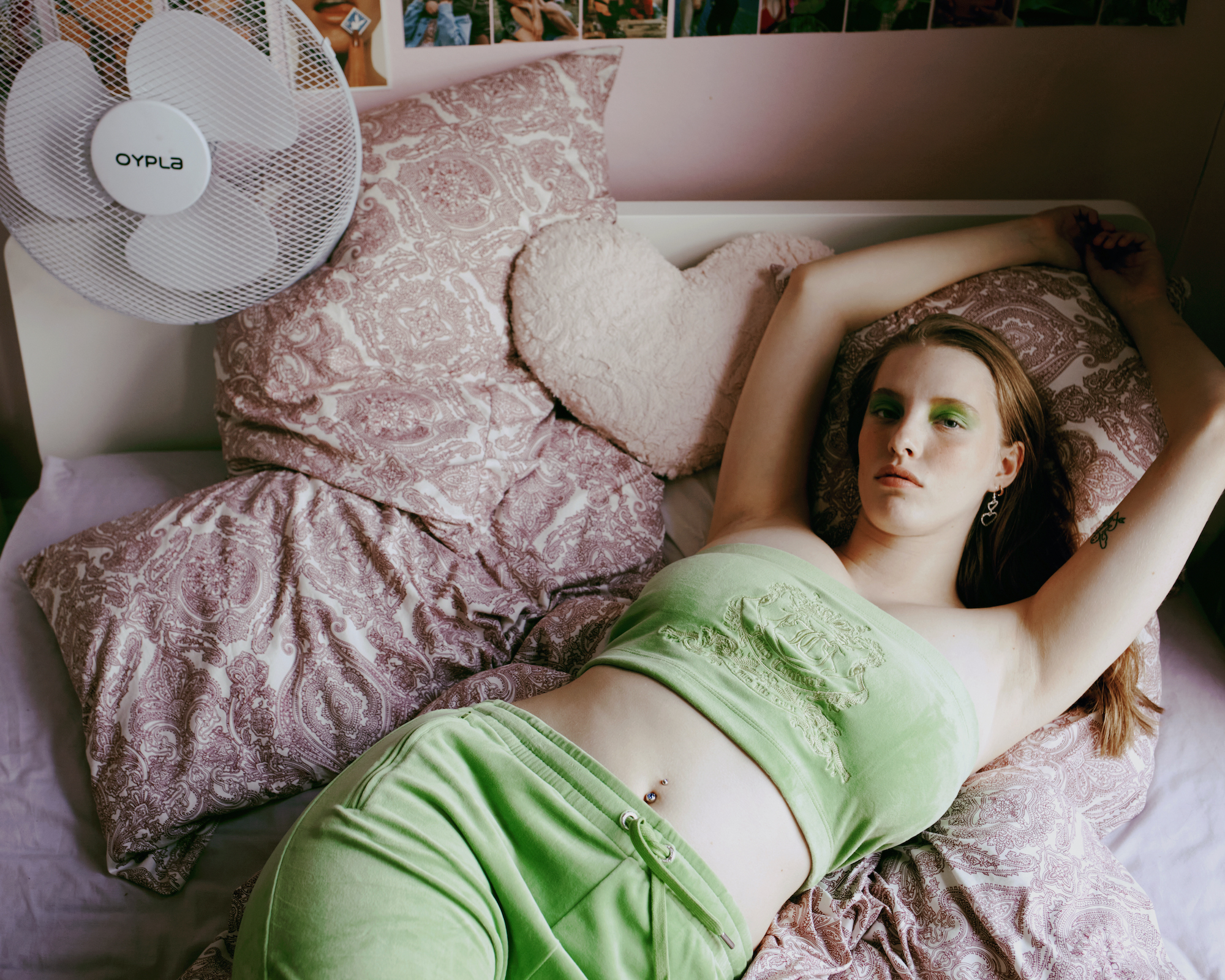 a girl in a green velour tracksuit reclines on a bed
