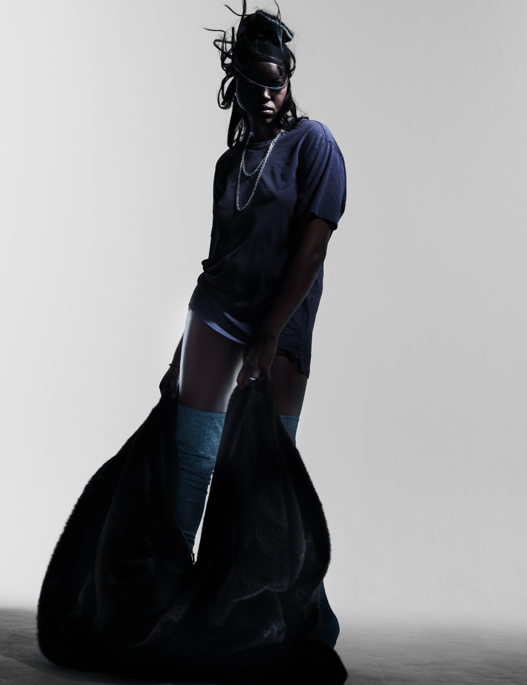 model poses in blue top with blue boots and black velvet overcoat. 