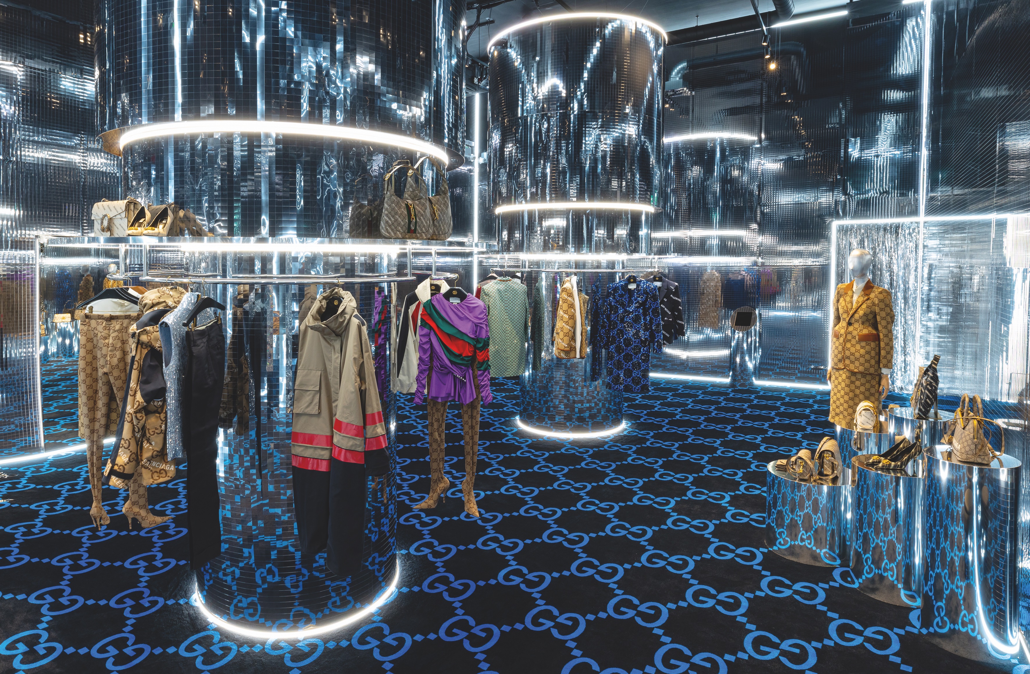 Inside the Gucci Circolo pop up shop with the GG monogram carpet and mirrored walls and clothes rails. with neon lights.