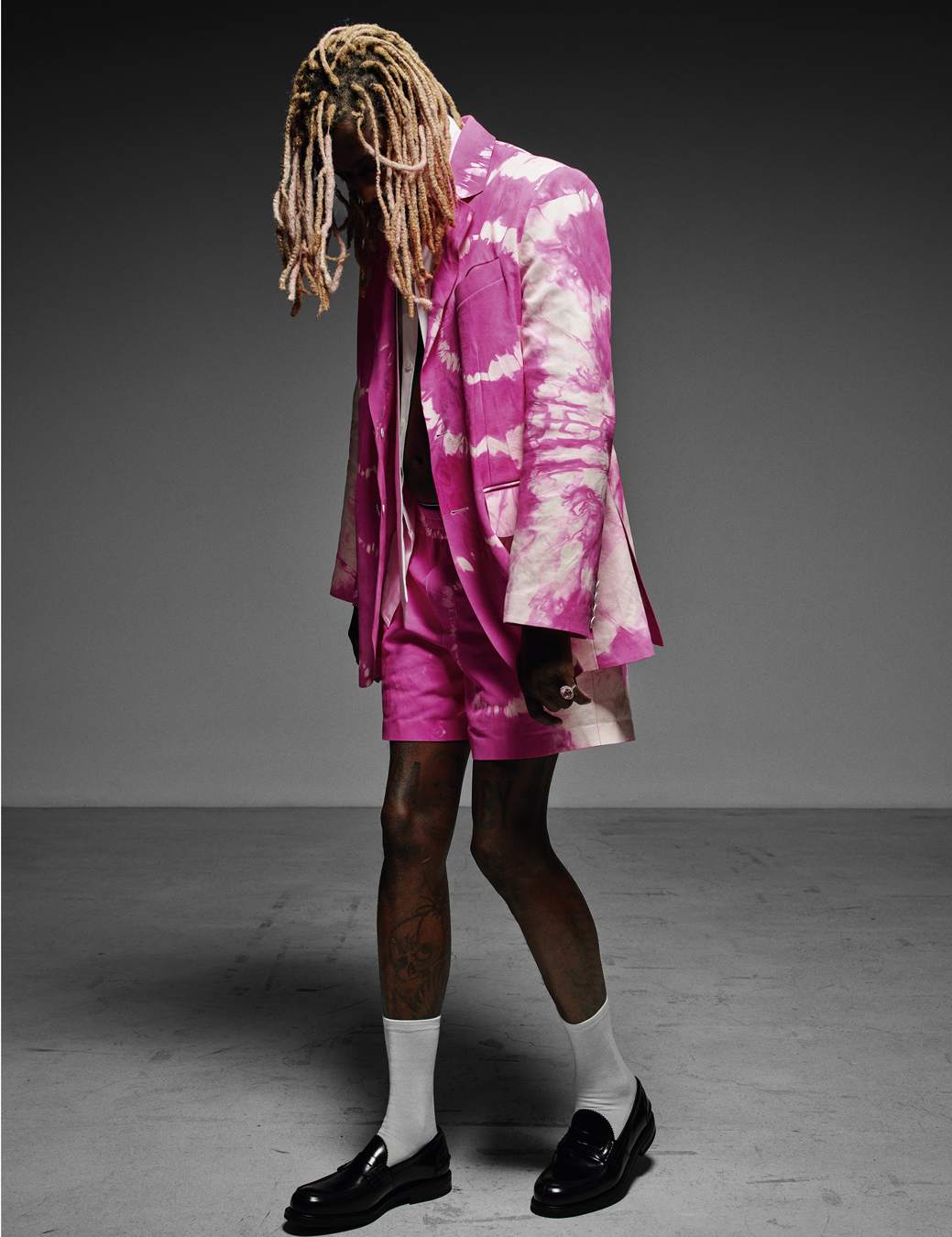 Young Thug wearing a hot pink acid wash blazer with matching shorts, white socks, and black shoes. 