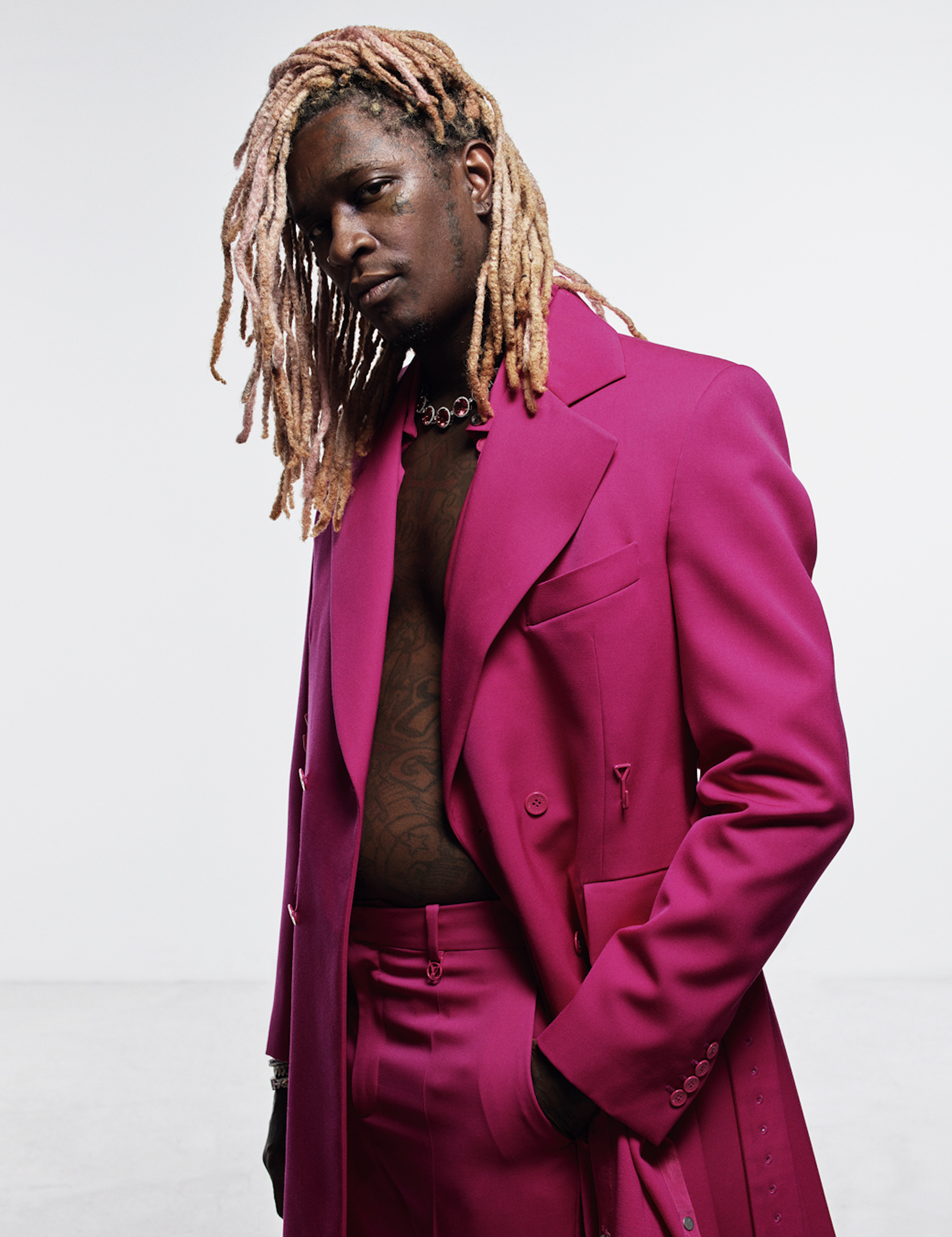 Young Thug wearing a hot pink suit and no shirt with Tiffany jewellery. 