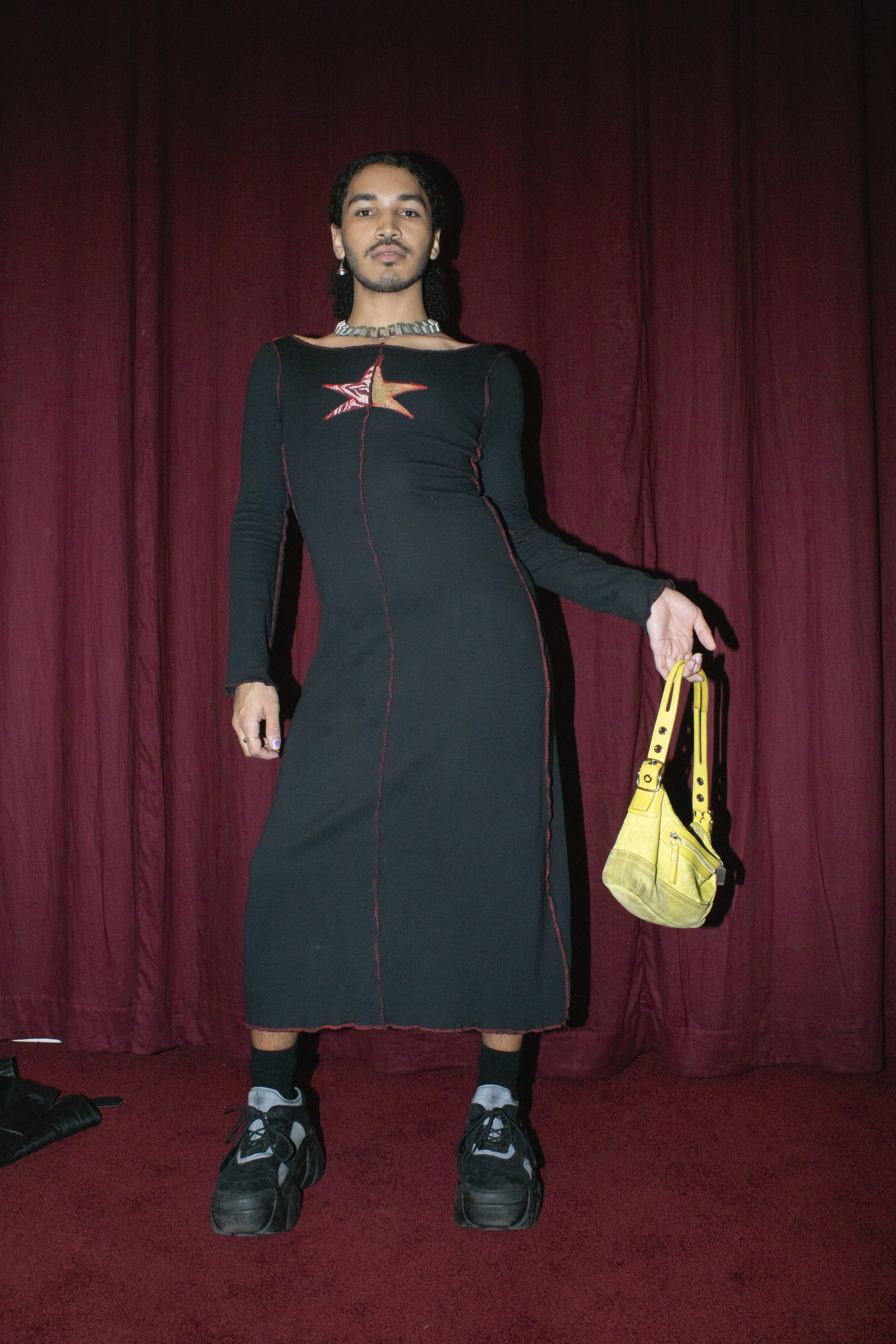 a person in a 90s style dress and platform buffalo trainers poses holding a yellow saddle bag 