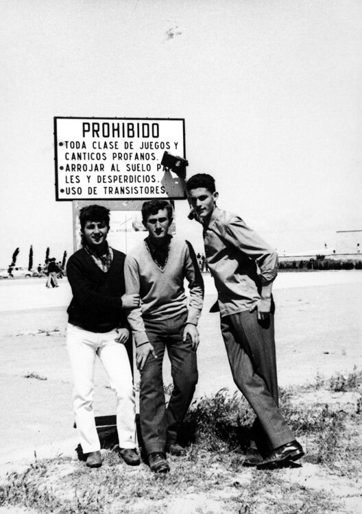 West Side Story, Madrid, gangs - Black and white photo of three smartly dressed men stood in front of a sign.