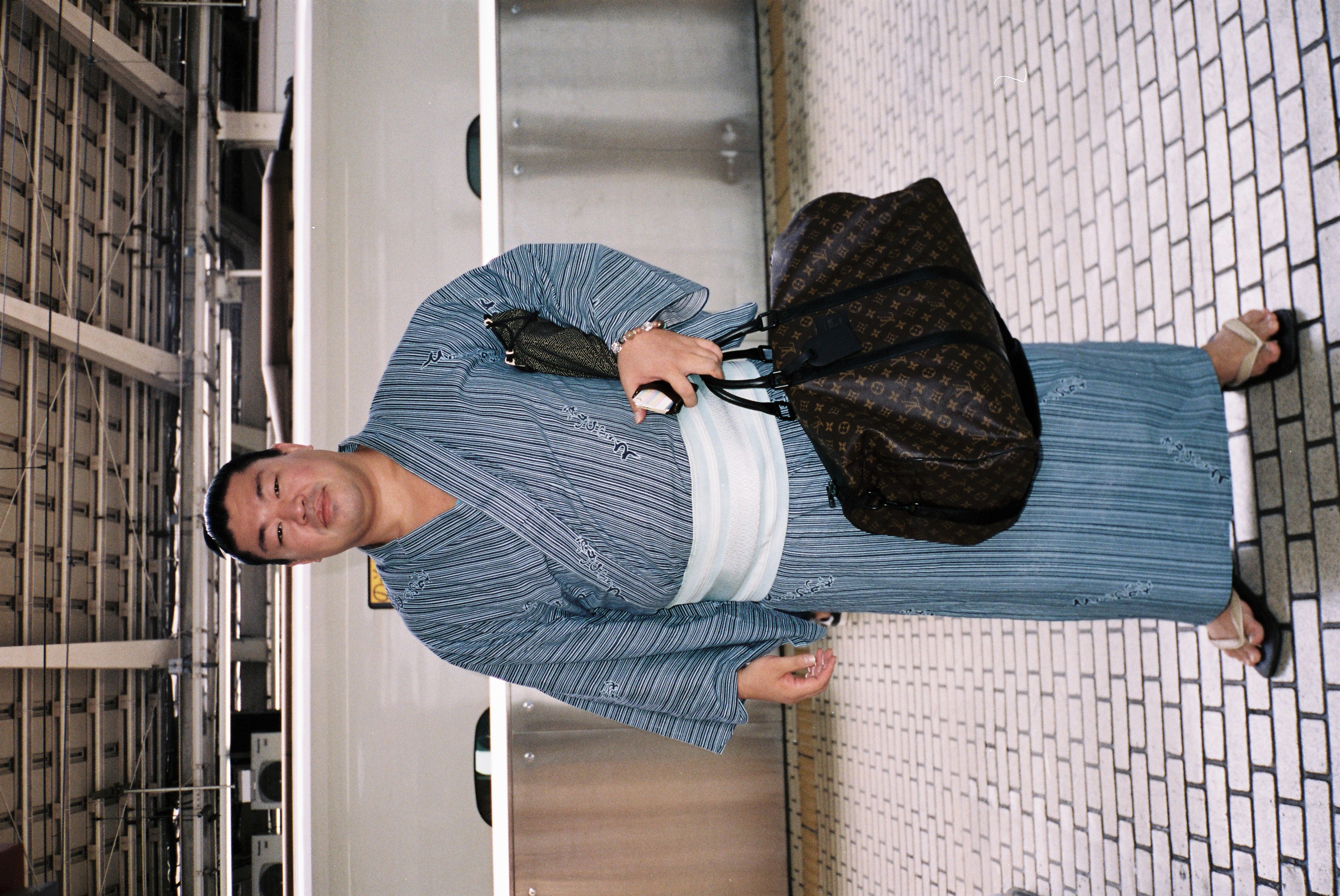 uomo asiatico con kimono a righe blu e borsa louis vuitton