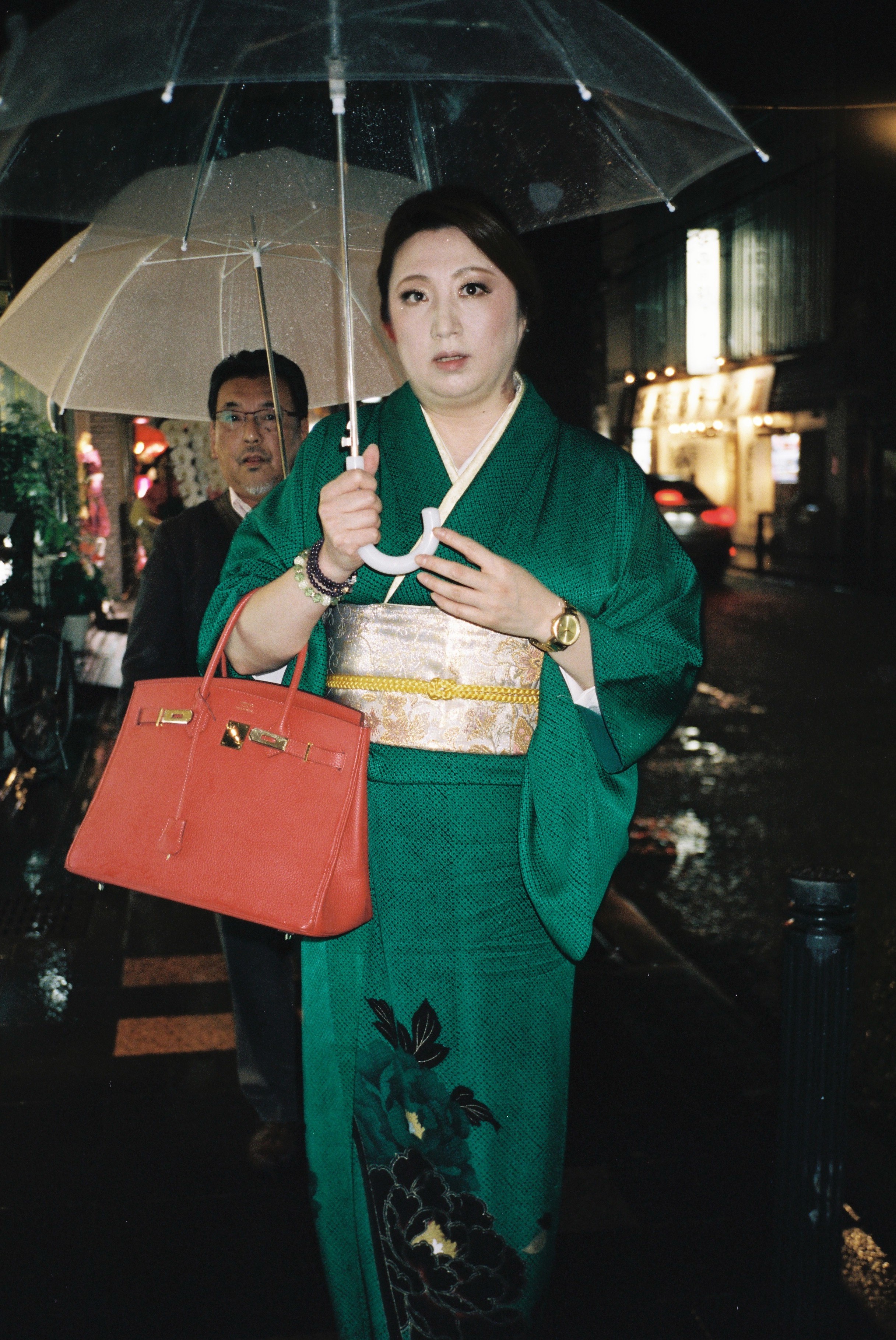 donna asiatica con kimono verde smeraldo ricamato e borsa hermes kelly