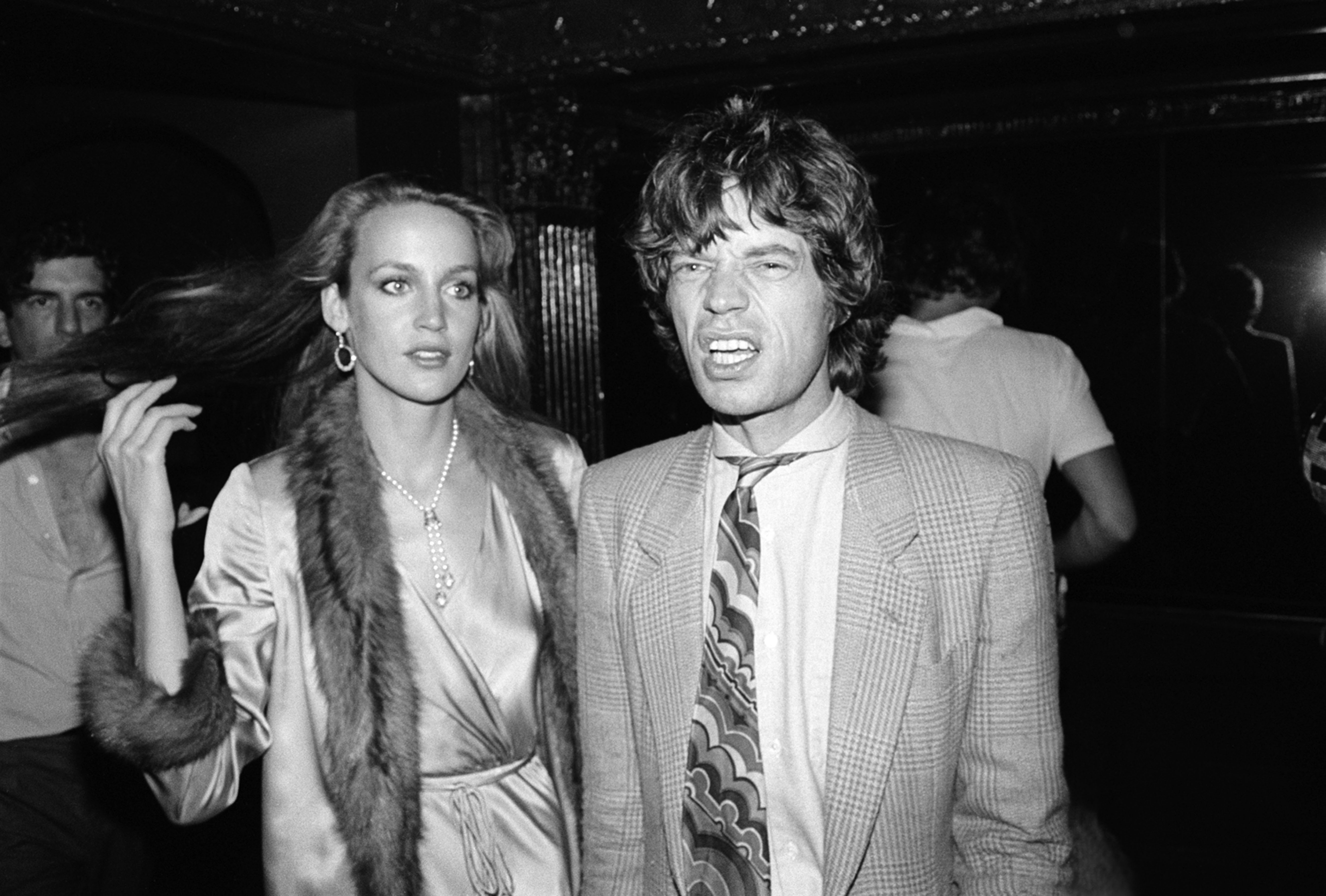 Jerry Hall flips his hair back in a fur-lined jacket with Mick Jagger at studio 54