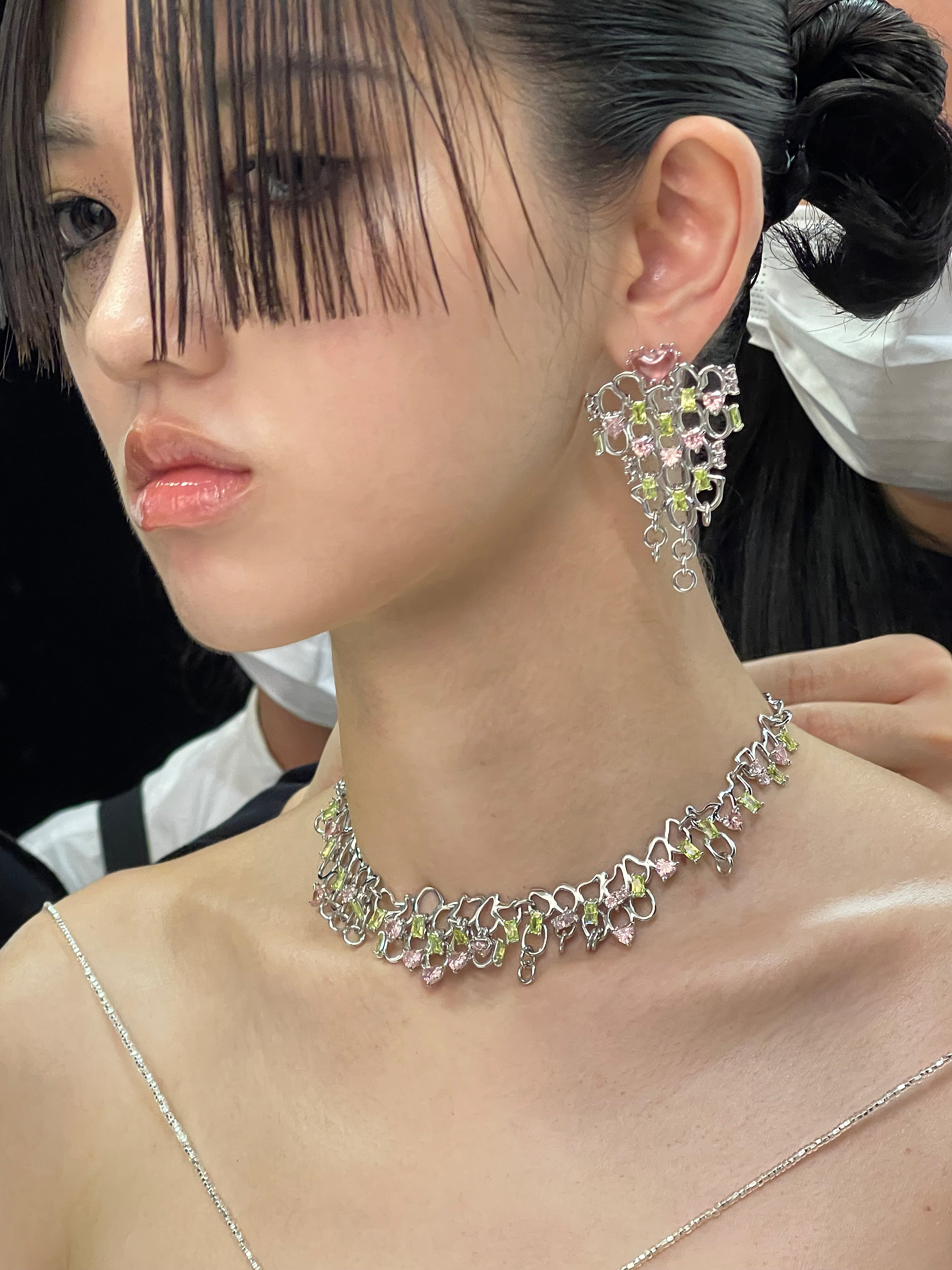 a model wearing a silver jewelled necklace and earrings by yvmin