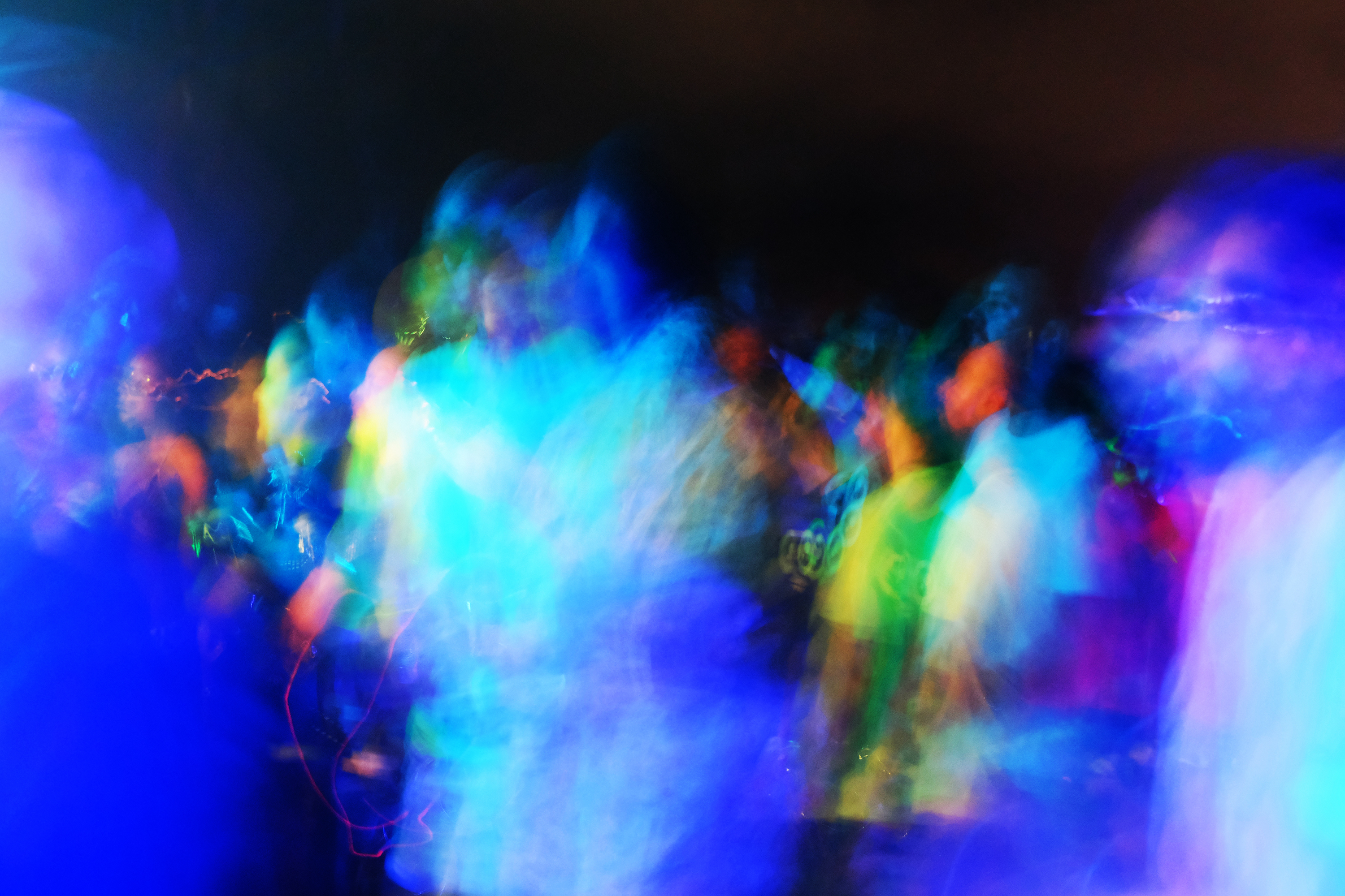 a long exposure shot of a group of people dancing at an EDM rave in Lagos
