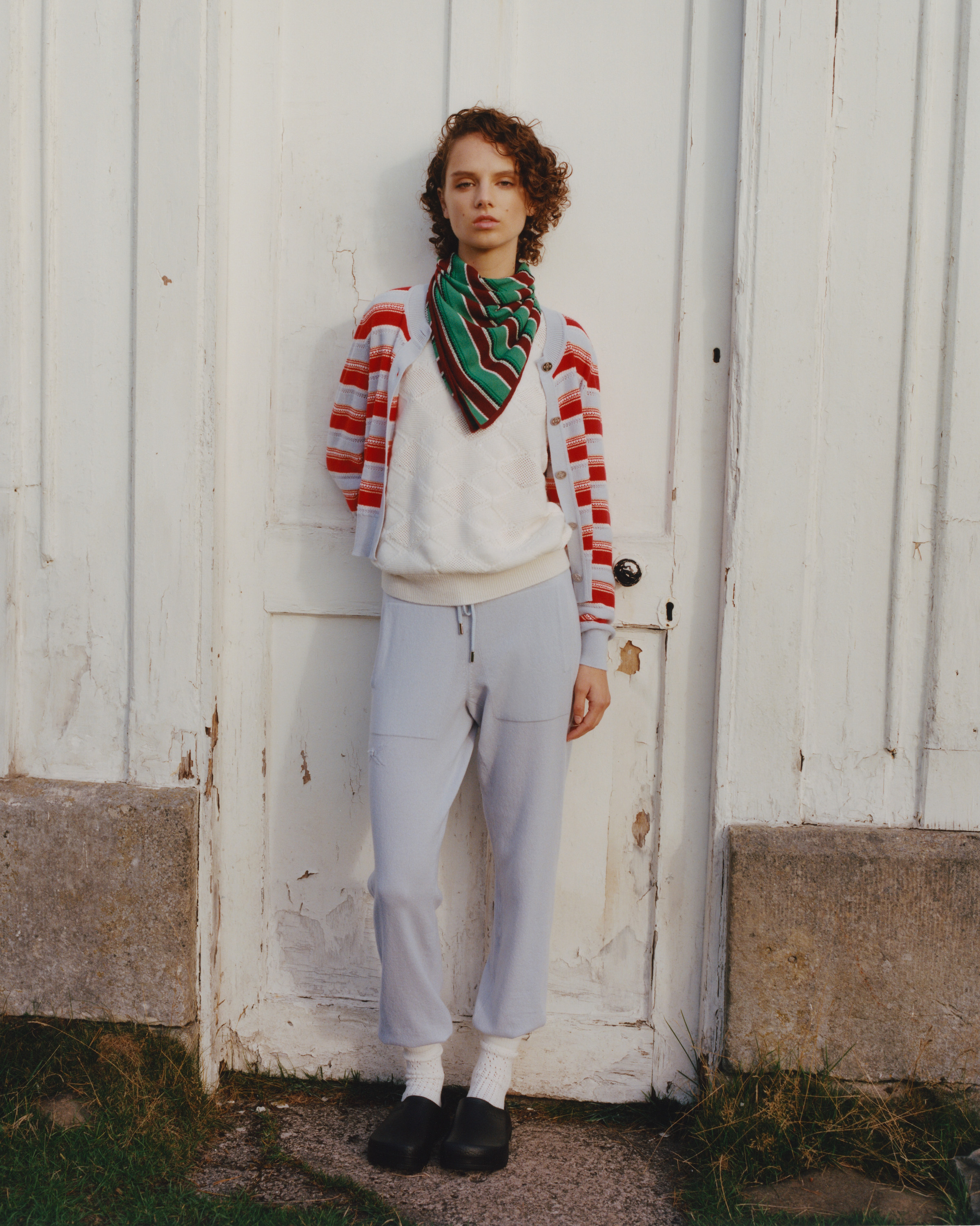 a model leaning against a wall wearing barrie cashmere
