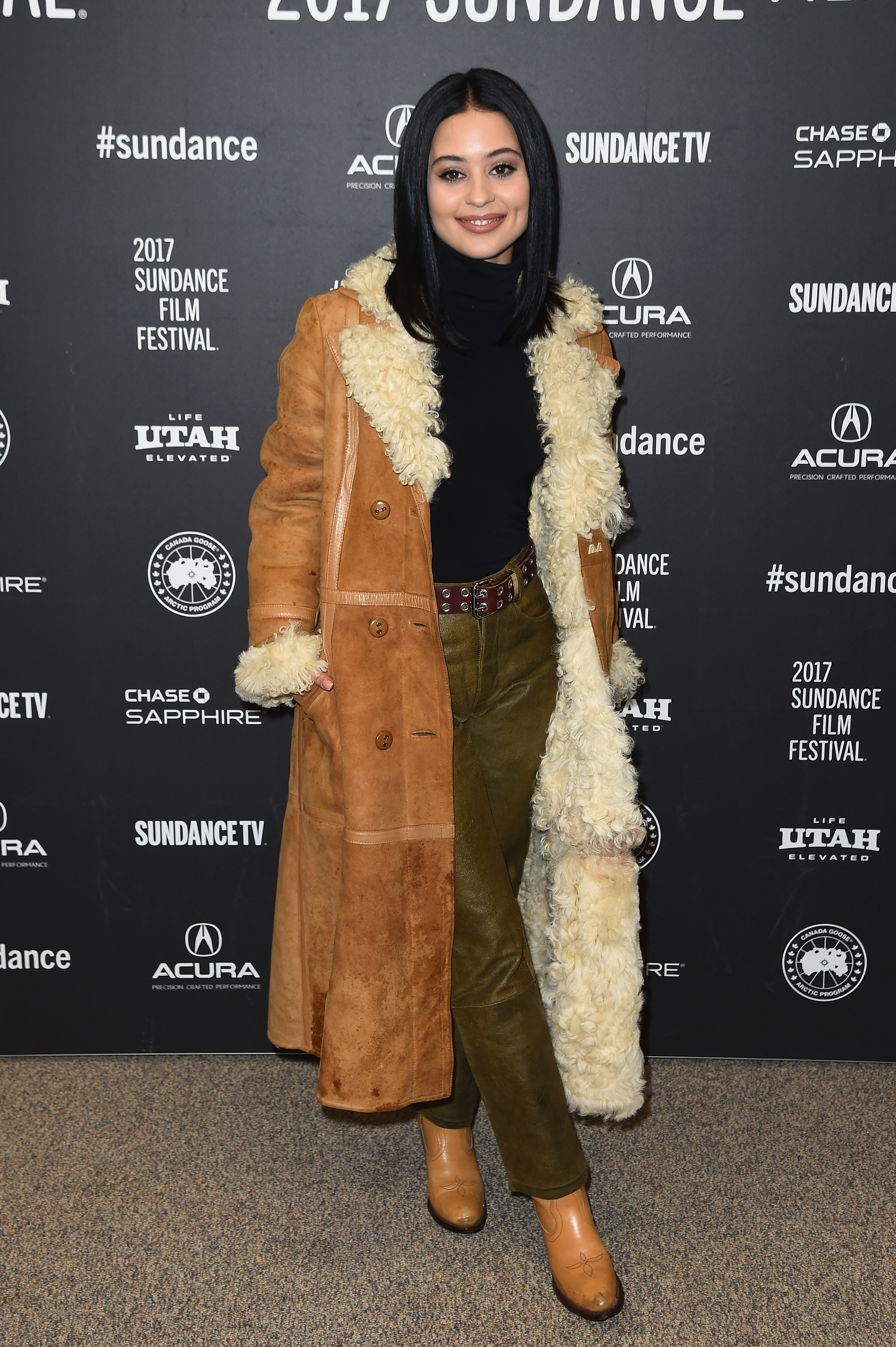 Alexa Demie at Sundance Film Festival 2017 wearing a black turtleneck, leather trousers, a tan coat and tan boots. 