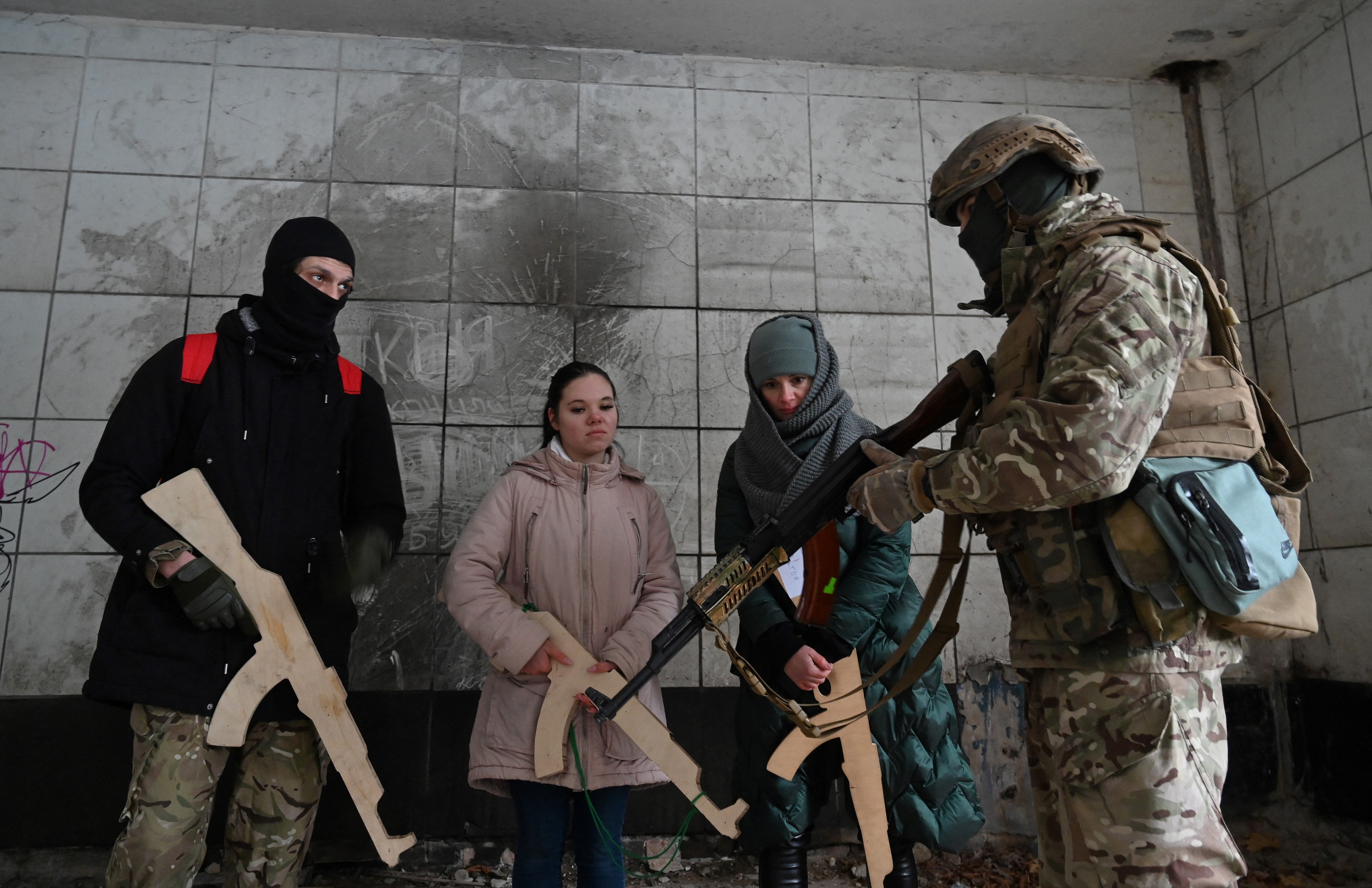 A military instructor teaches civilians holding wooden replicas of Kalashnikov rifles, during a training session at an abandoned factory in the Ukrainian capital of Kyiv.