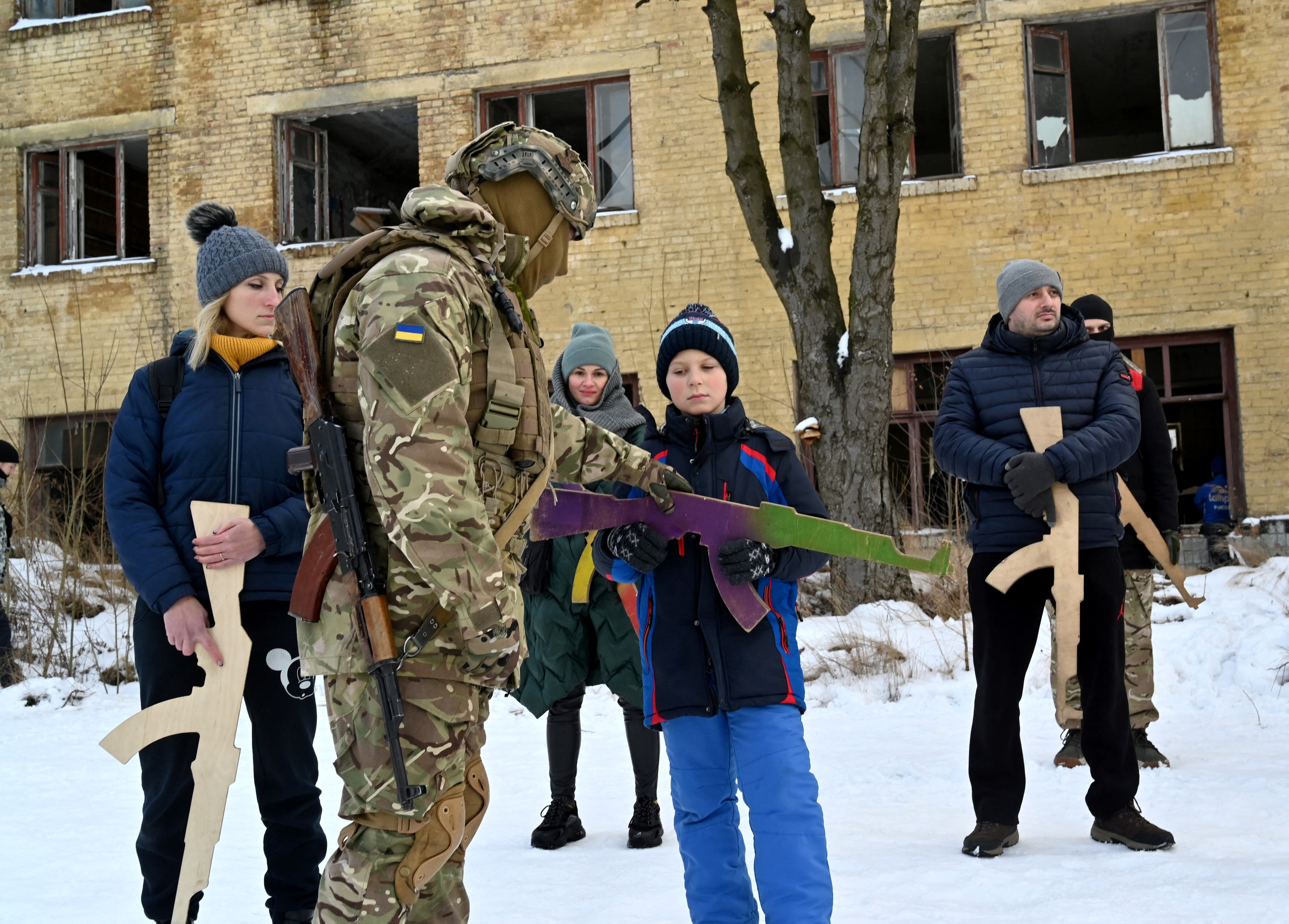 A military instructor teaches civilians holding wooden replicas of Kalashnikov rifles, as they take part in a training session at an abandoned factory in the Ukrainian capital of Kyiv