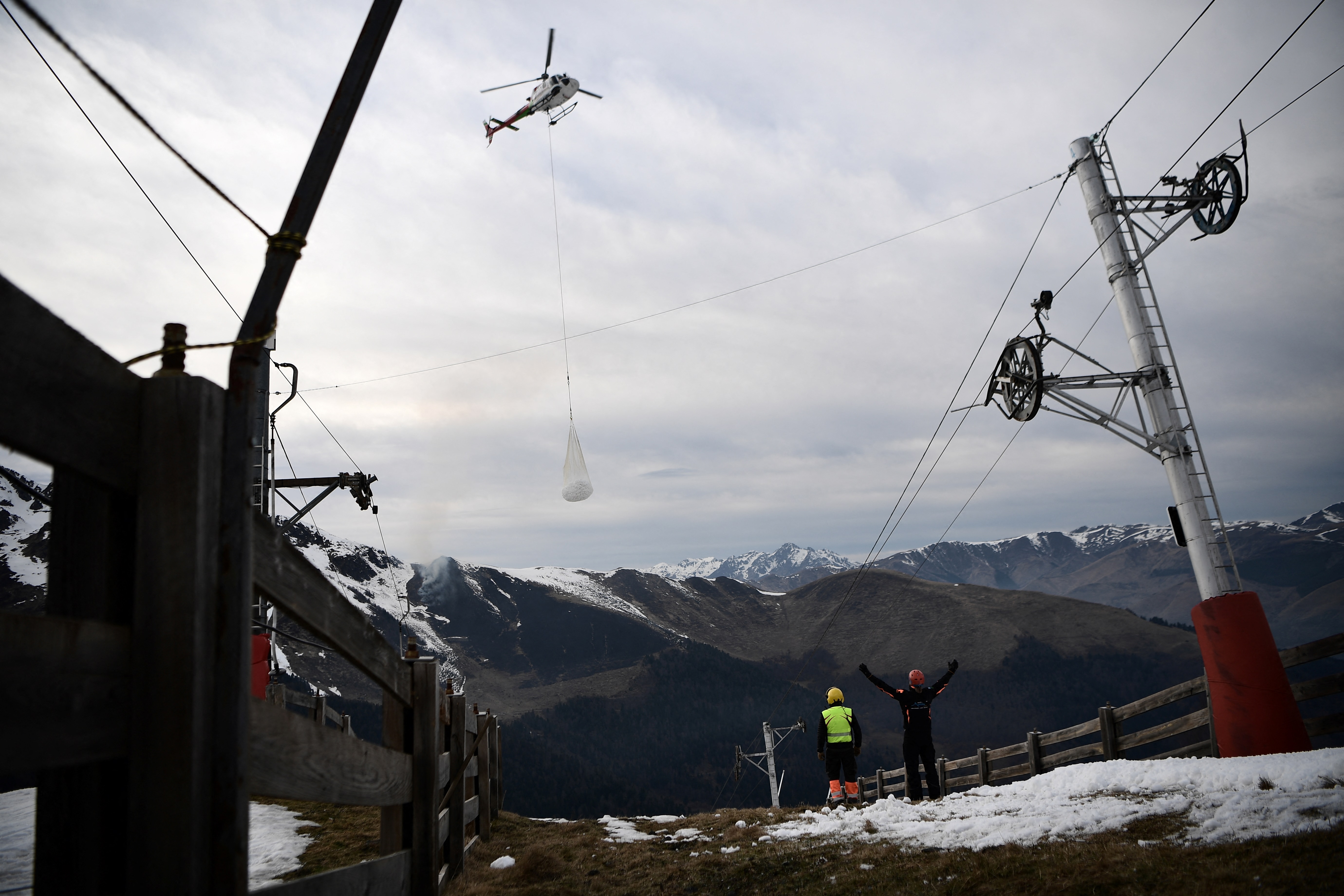 A helicopter carries snow to a ski slope in the French Pyrenees to make up for the lack of snow in February 2020. Photo: Anne-Christine POUJOULAT / AFP