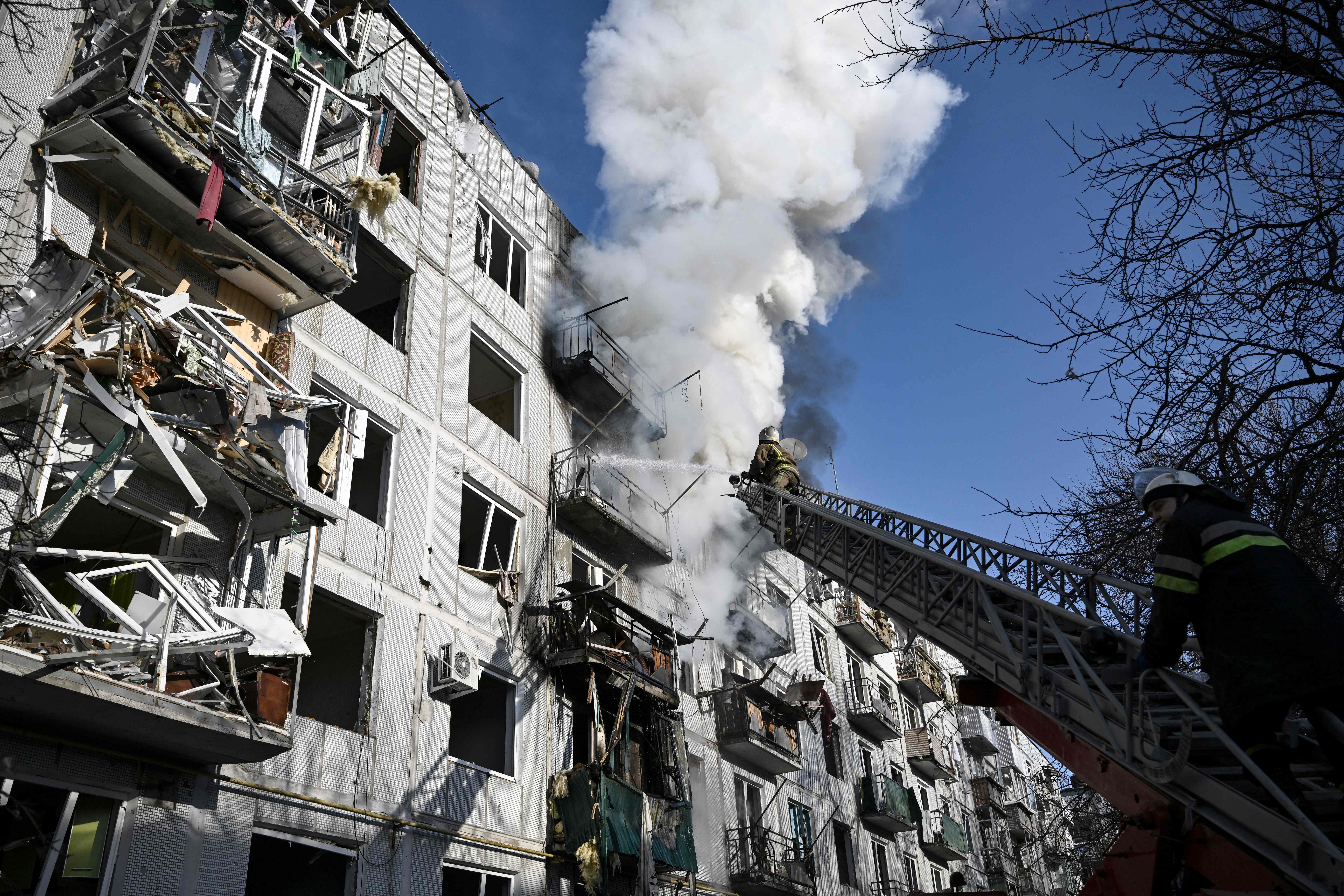 Firefighters work on a fire on a building after bombings on the eastern Ukraine town of Chuguiv on February 24, 2022