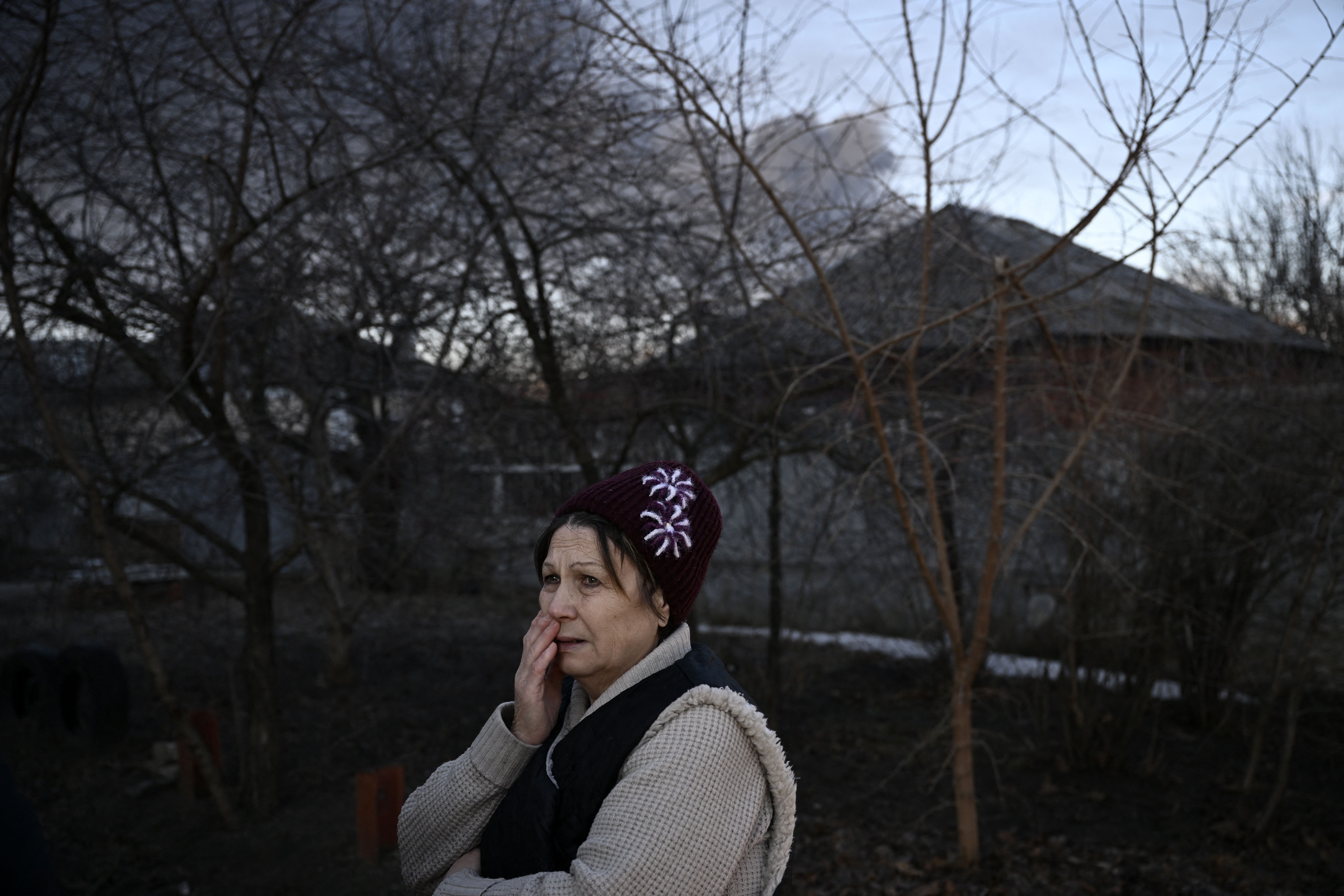 GettyImA woman stands in a street as black smoke rises from a military airport in Chuguyev near Kharkiv on February 24, 2022ages-1238719152.jpg