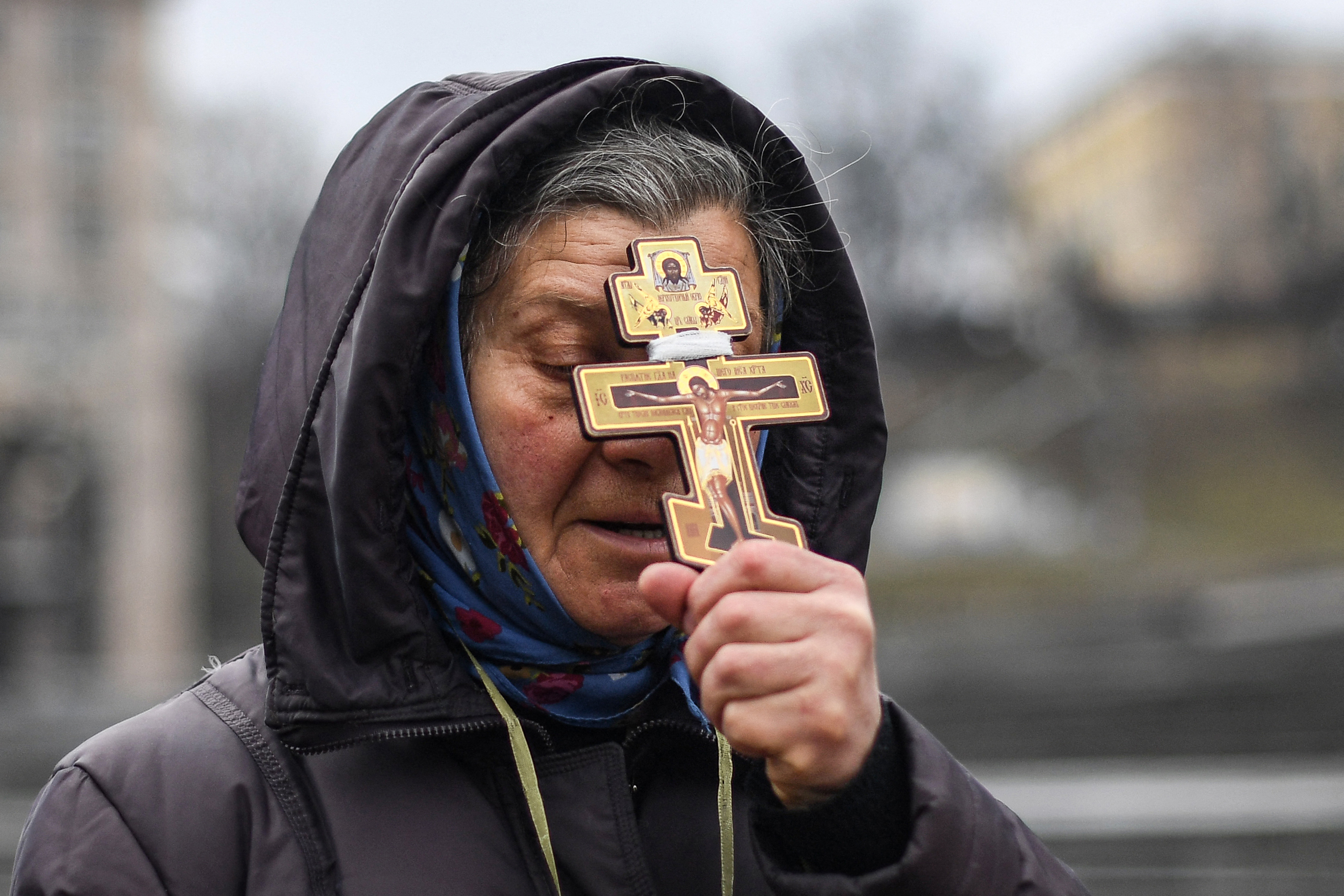 A religious woman holds a cross as she prays on Independence square in Kyiv in the morning of February 24, 2022