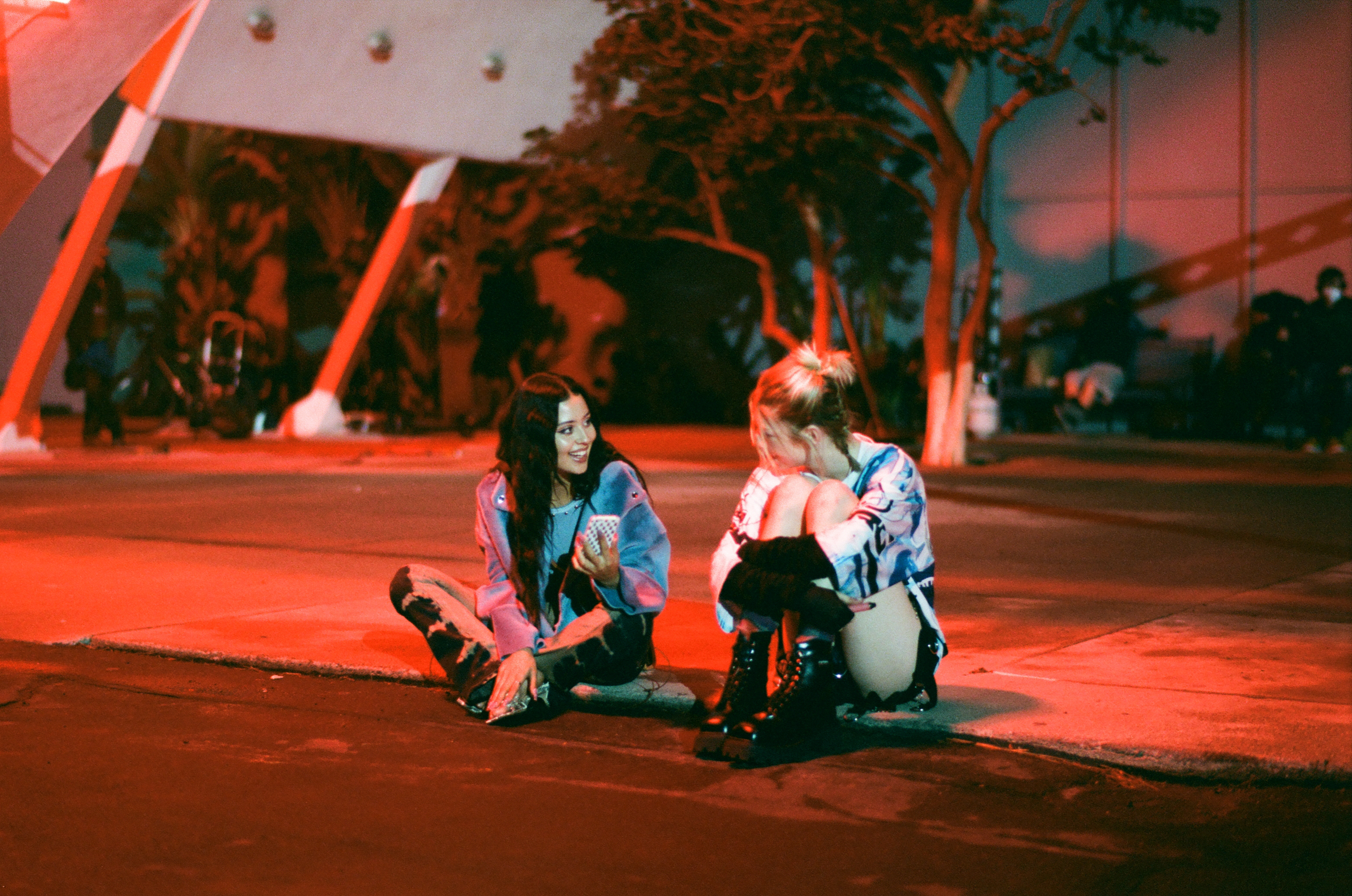 Alexa Demie and Hunter Schafer on the red-lit pavement 