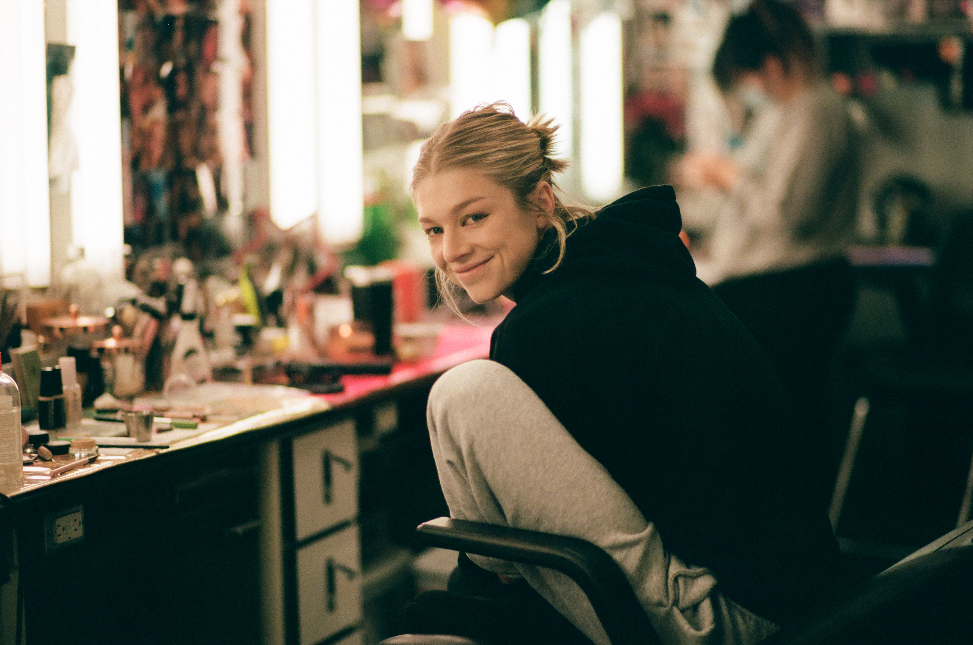 Hunter Schafer smiles while in the dressing chair