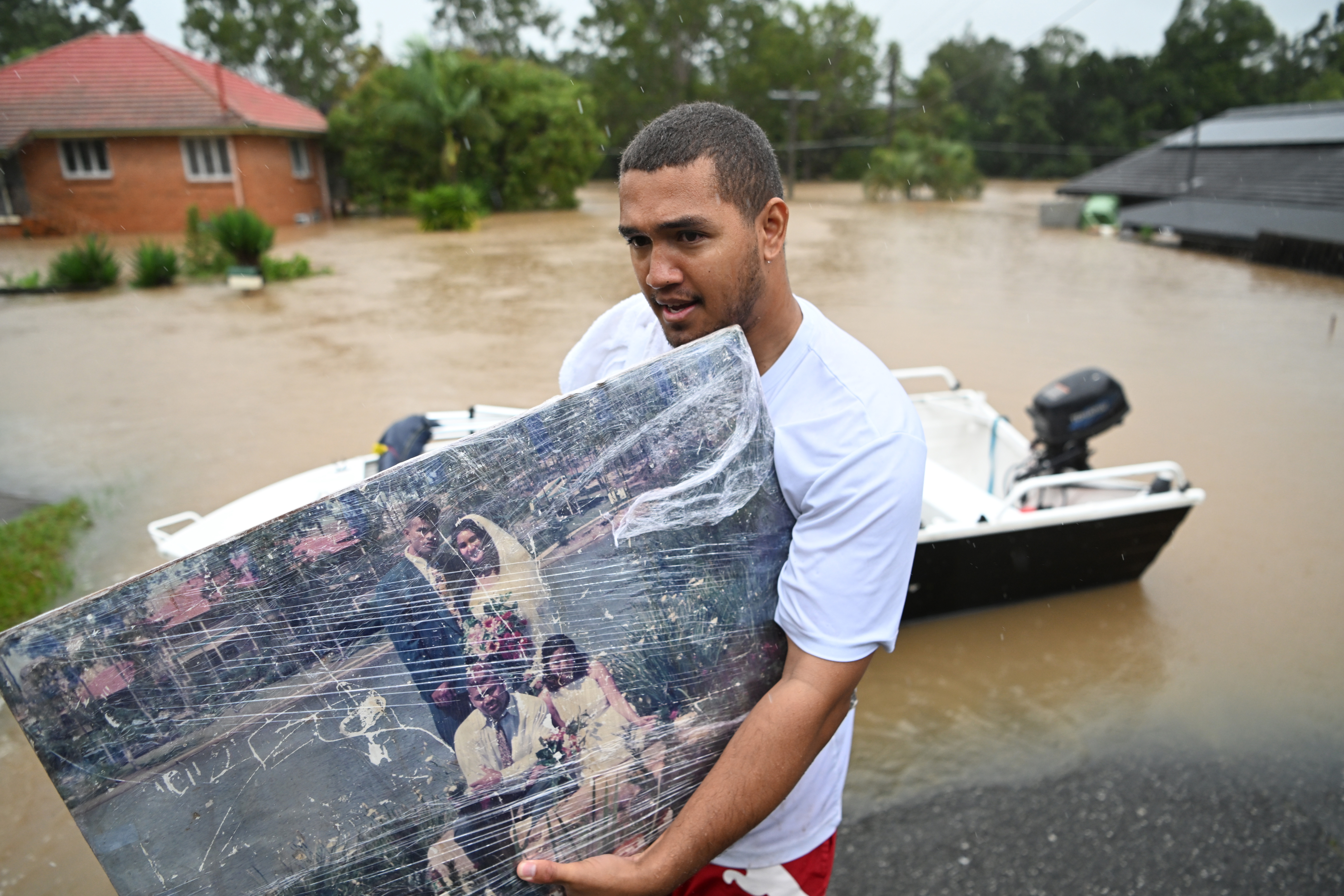 Lelaki menyelamatkan foto pernikahan dari rumahnya yang terendam banjir di Brisbane. Foto: Dan Peled/Getty Images