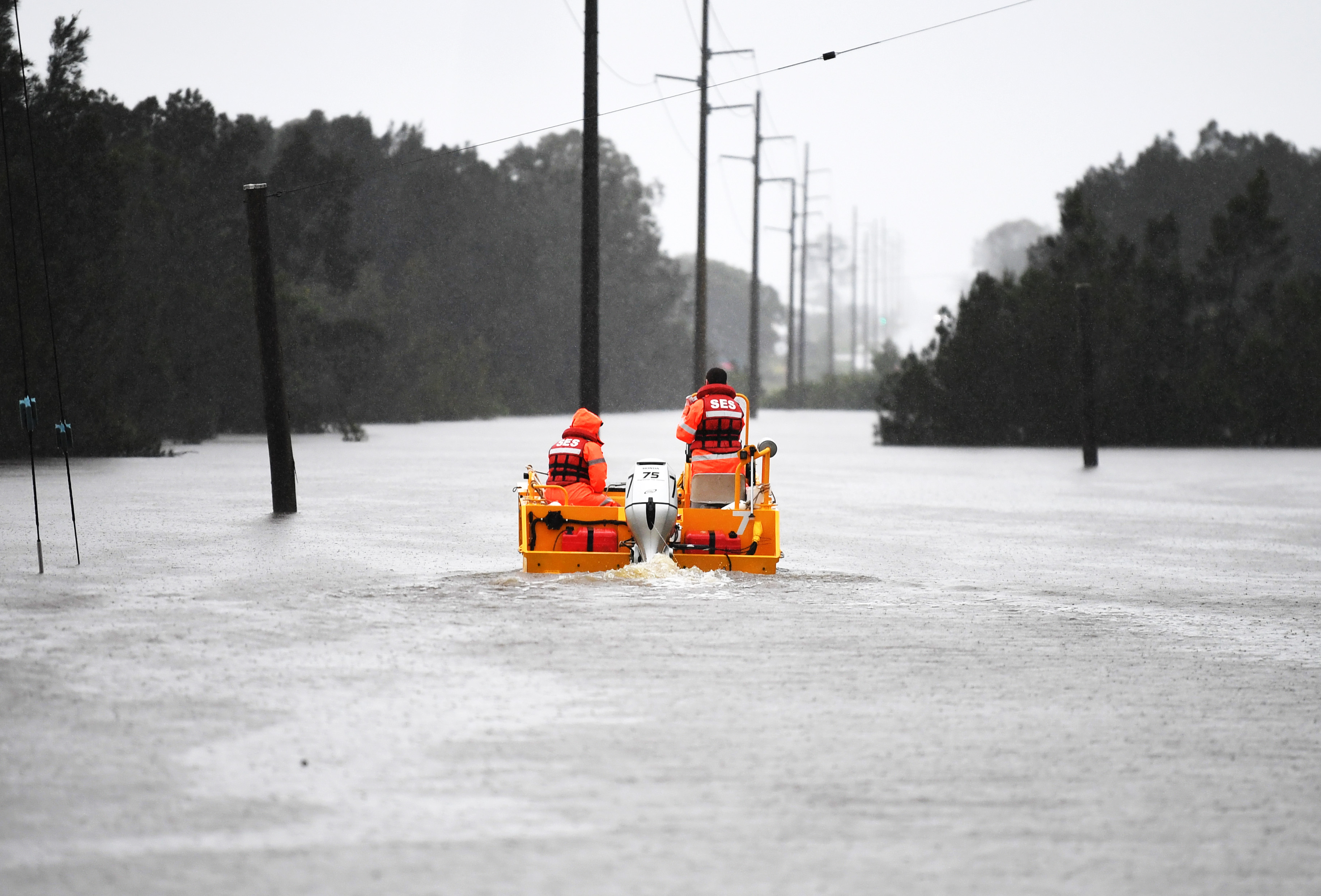 Anggota Layanan Darurat Negara Bagian (SES) mengarungi banjir di Brisbane. Foto: Dan Peled/Getty Images