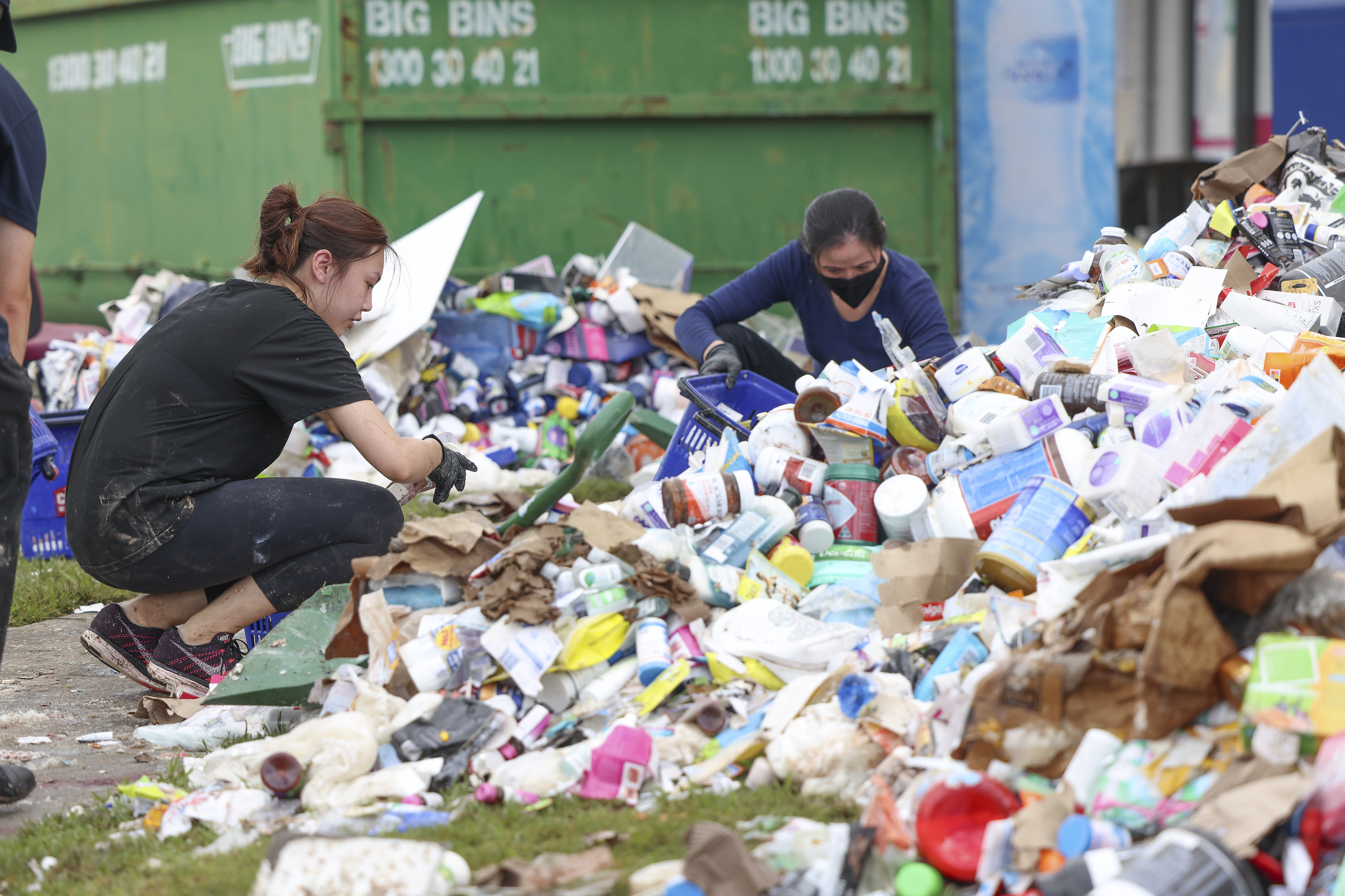 Dua karyawan membersihkan sampah yang hanyut terbawa banjir di gudang kimia di Brisbane. Foto: Peter Wallis/Getty Images