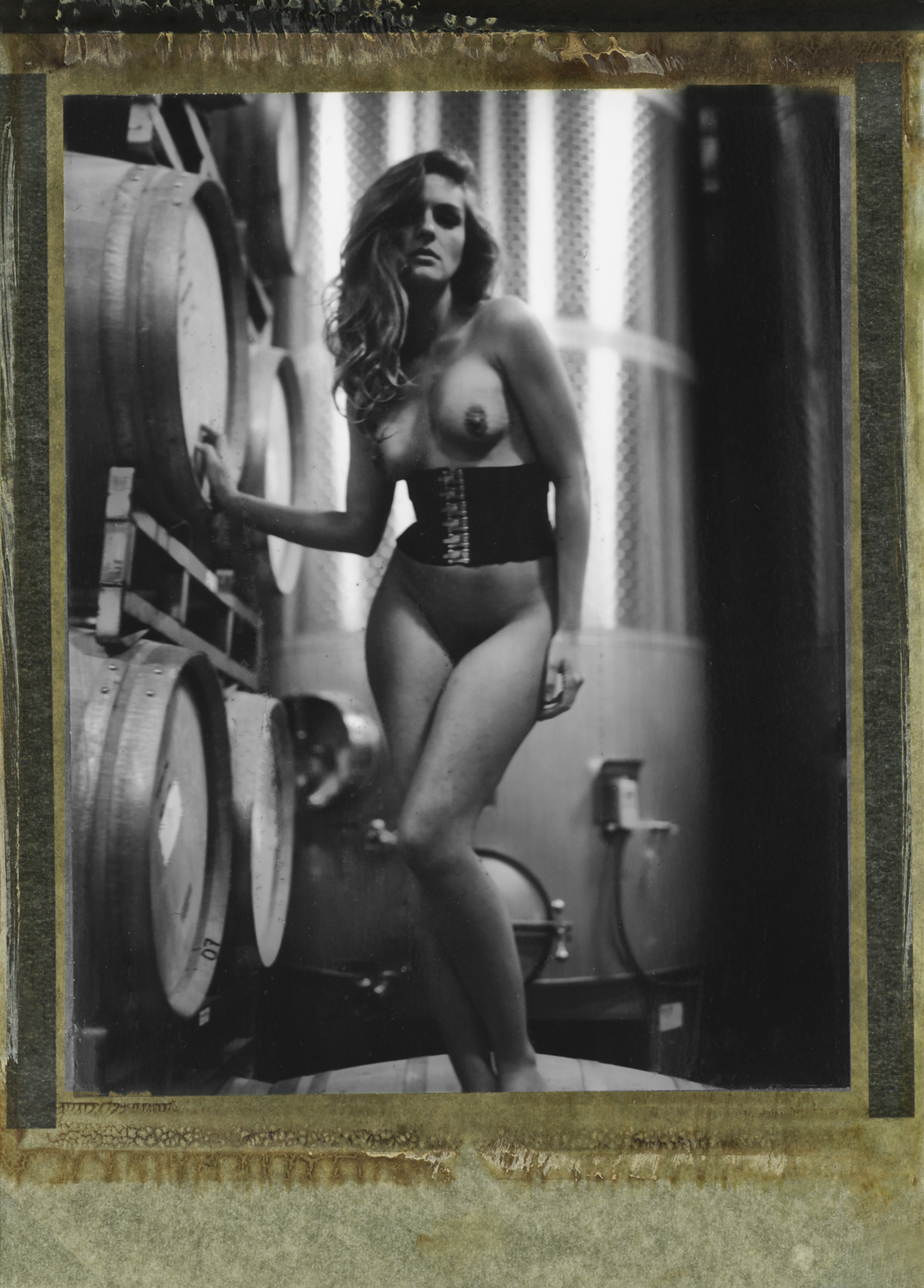 a naked woman stands next to barrels wearing a corset around her waist