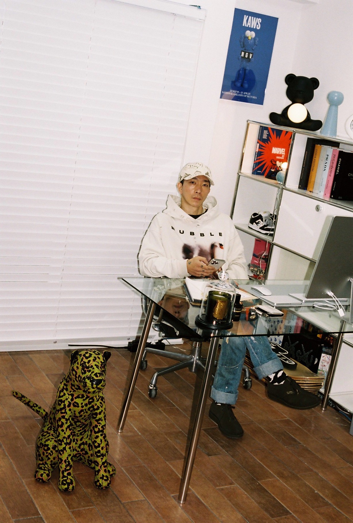 stylist wook kim sits behind a glass desk with a leopard statue by his side