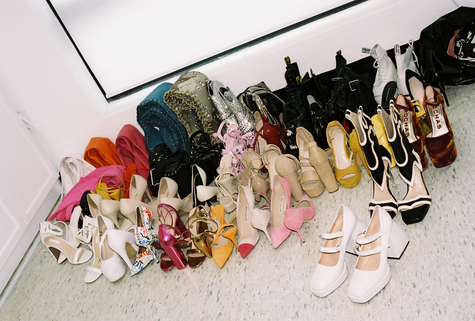 the corner of a room is filled with colourful pairs of womens shoes 