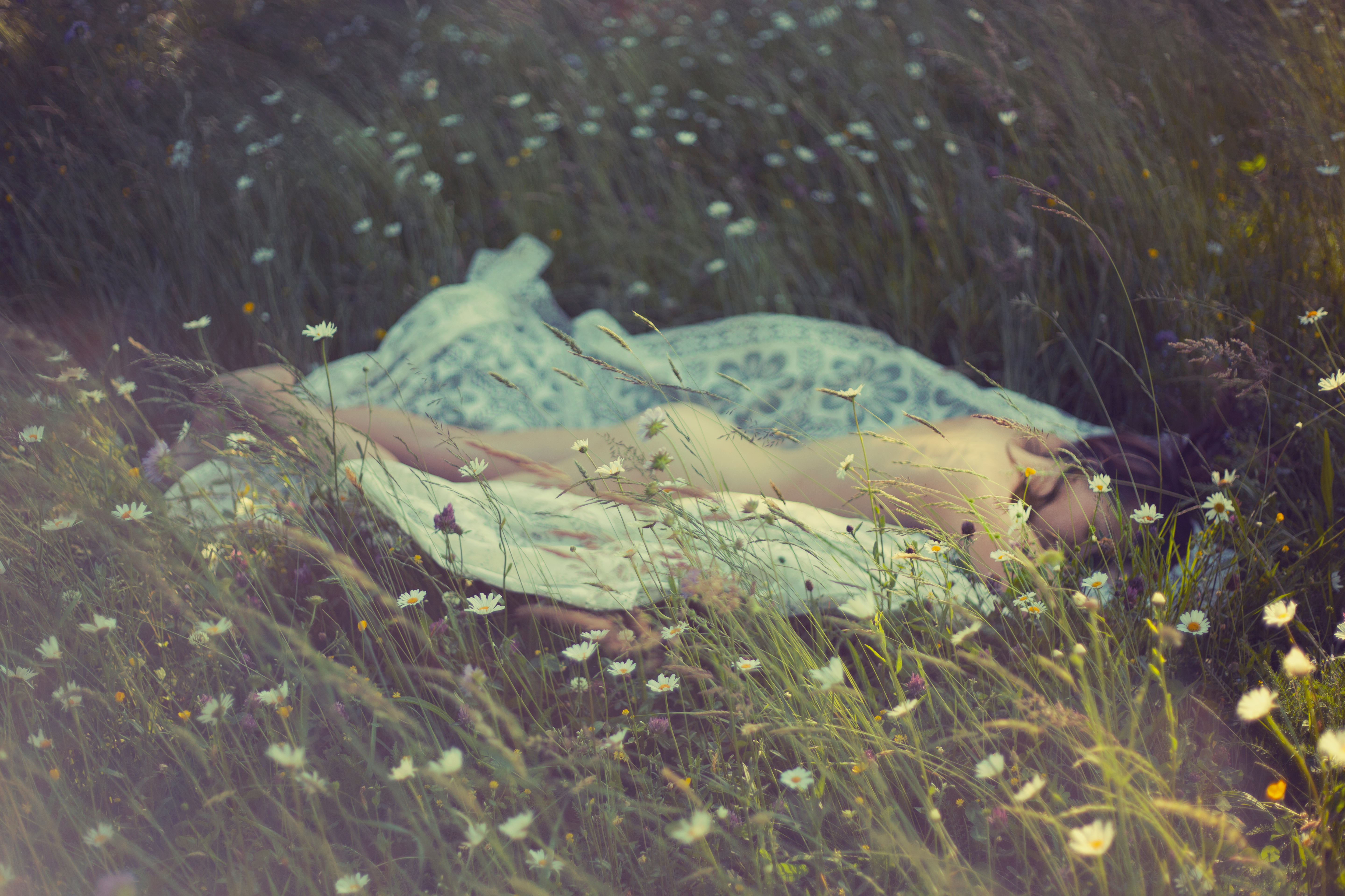 a woman lies in the grass on a picnic blanket