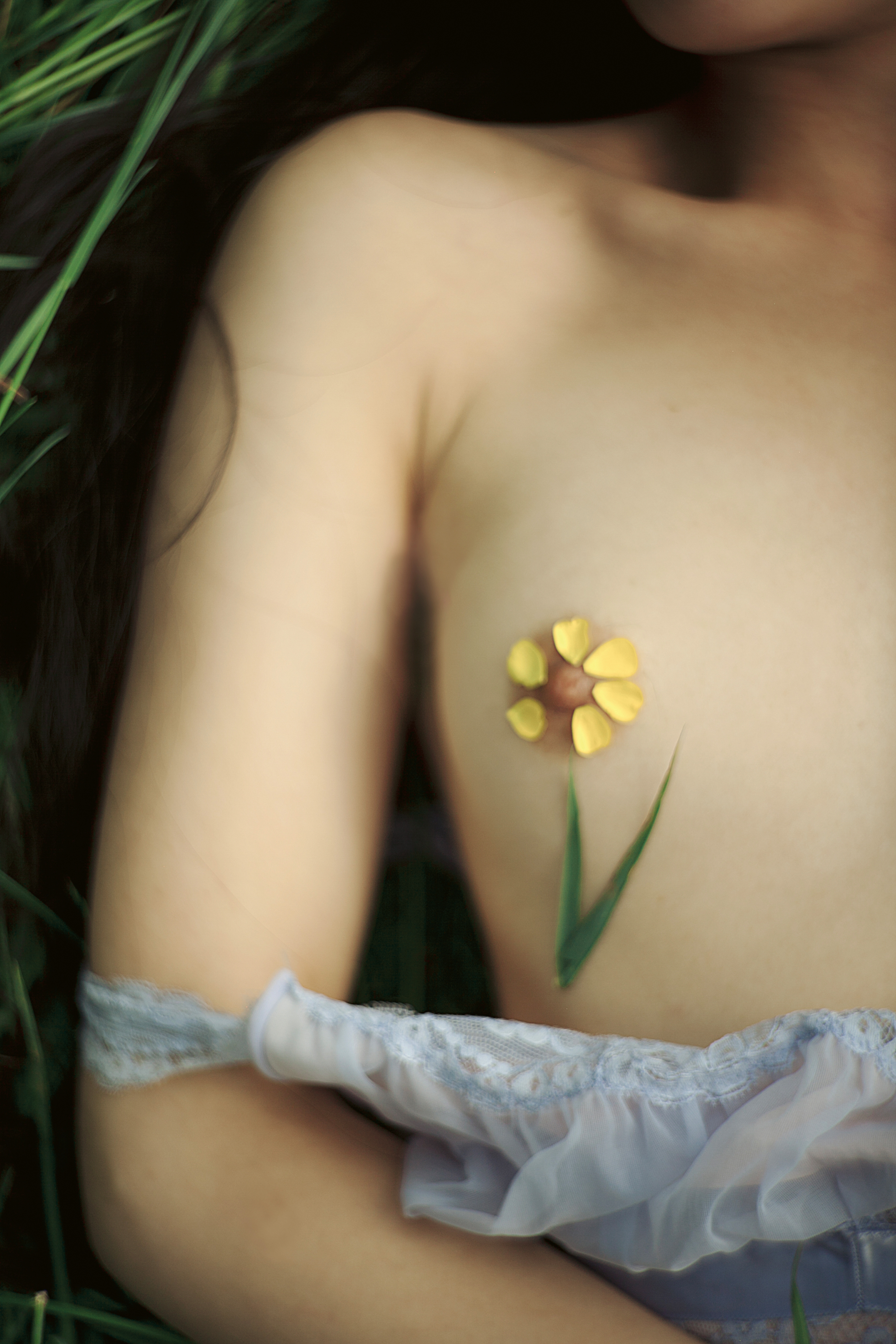 a flower built around a nipple as a girl lays on the grass