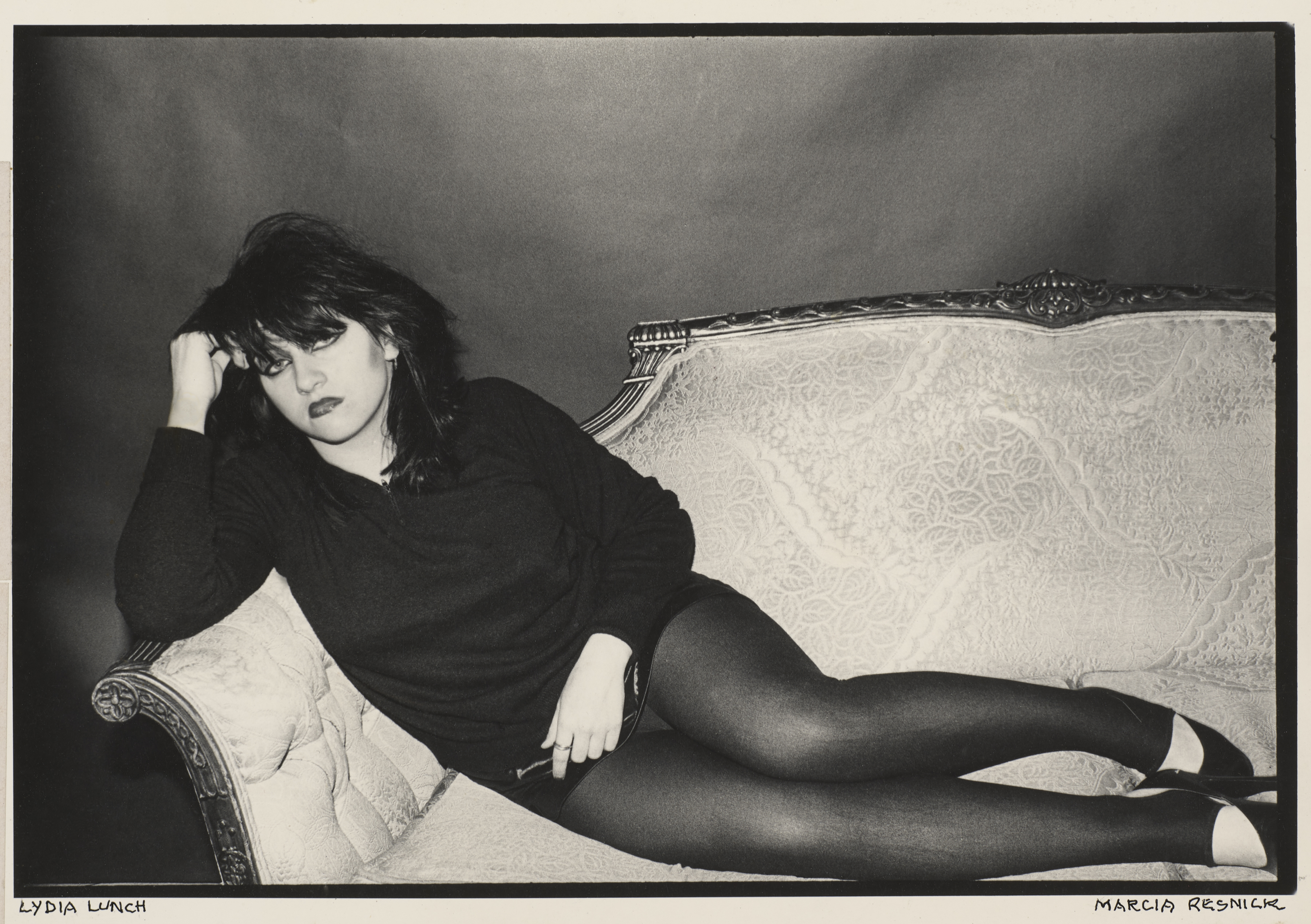 Photograph of Lydia Lunch lying on a chase lounge photographed by Marcia Resnick.