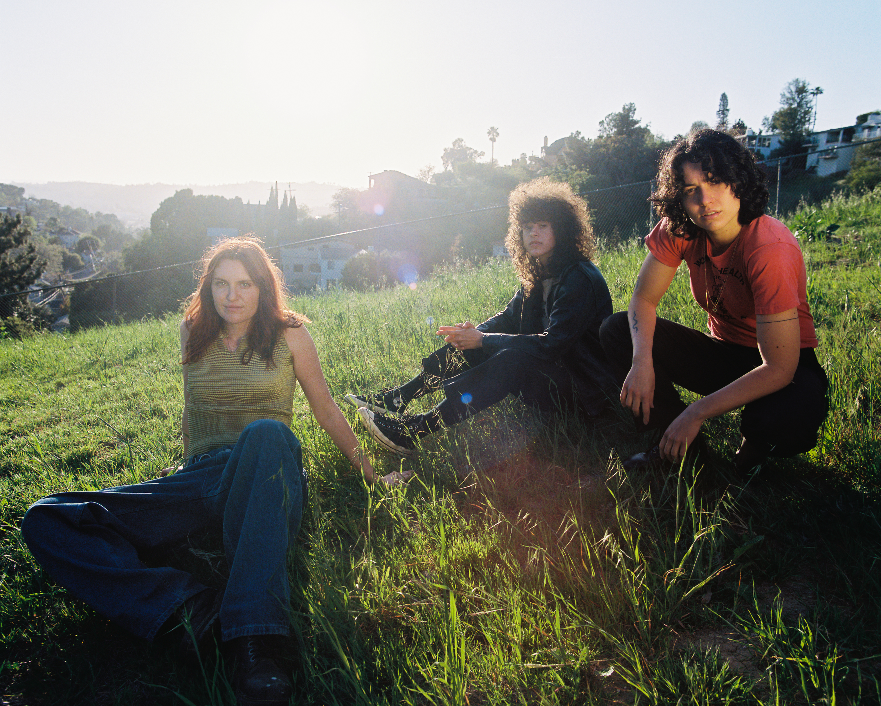 the band muna lying in grass in los angeles