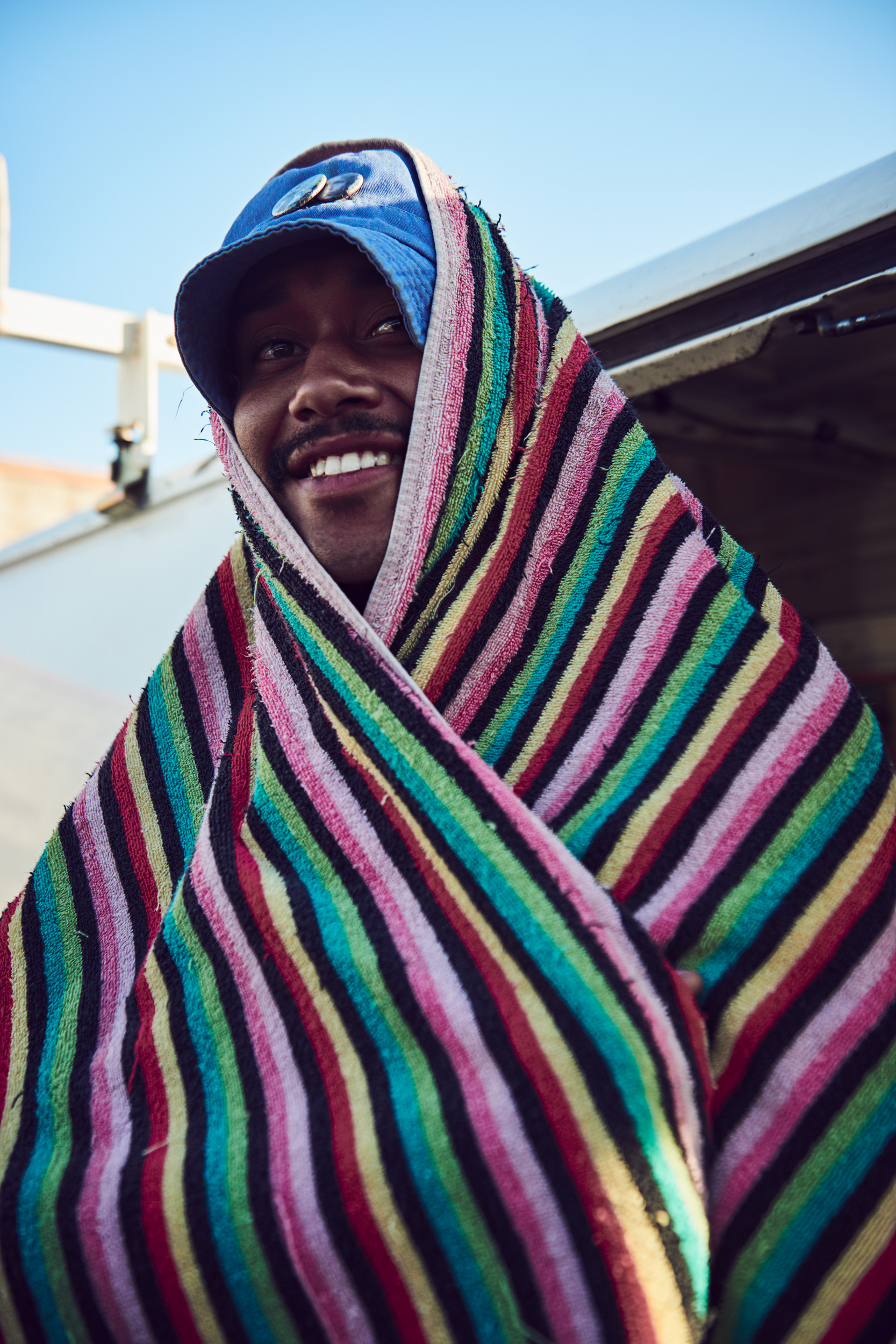A man wrapped in a colorful blanket wearing sunglasses.