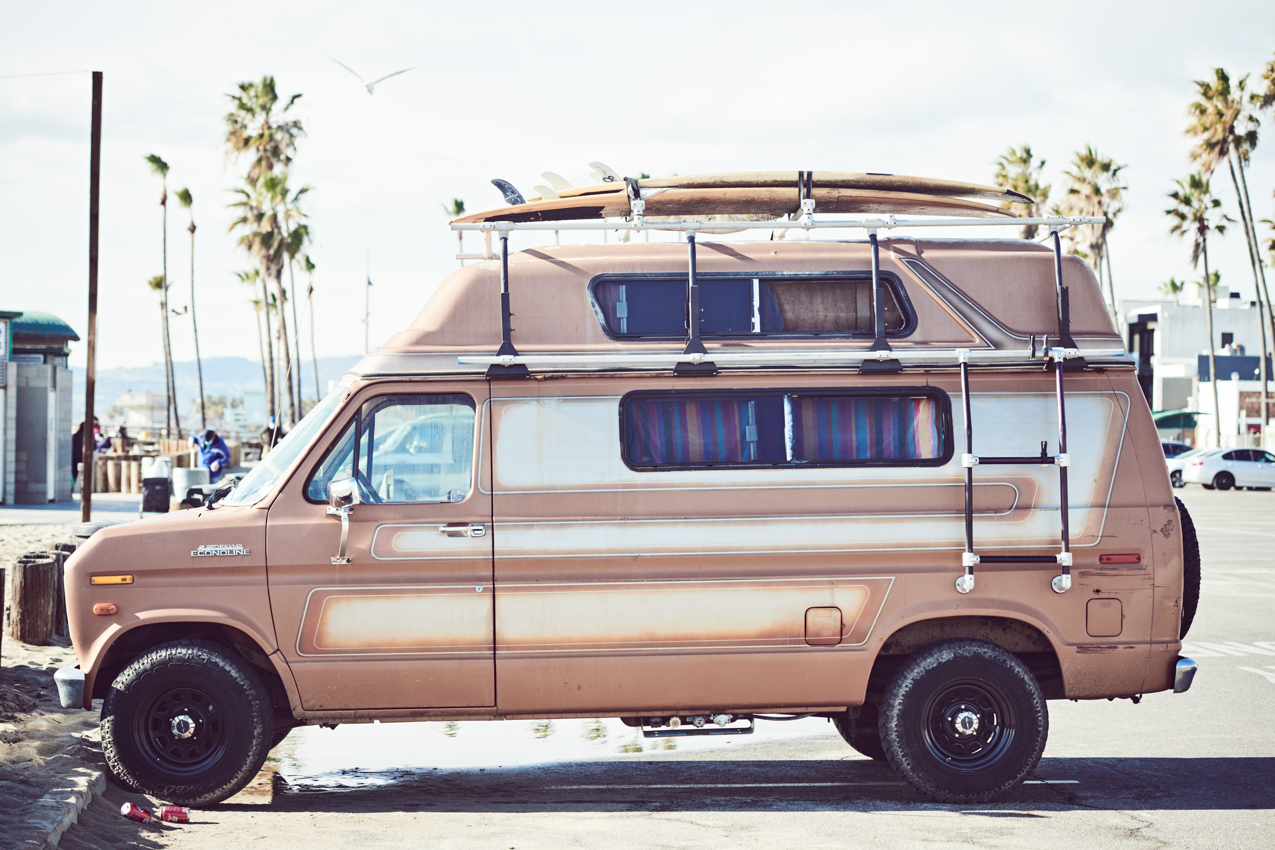 A surf van parked in a Venice Beach parking lot.