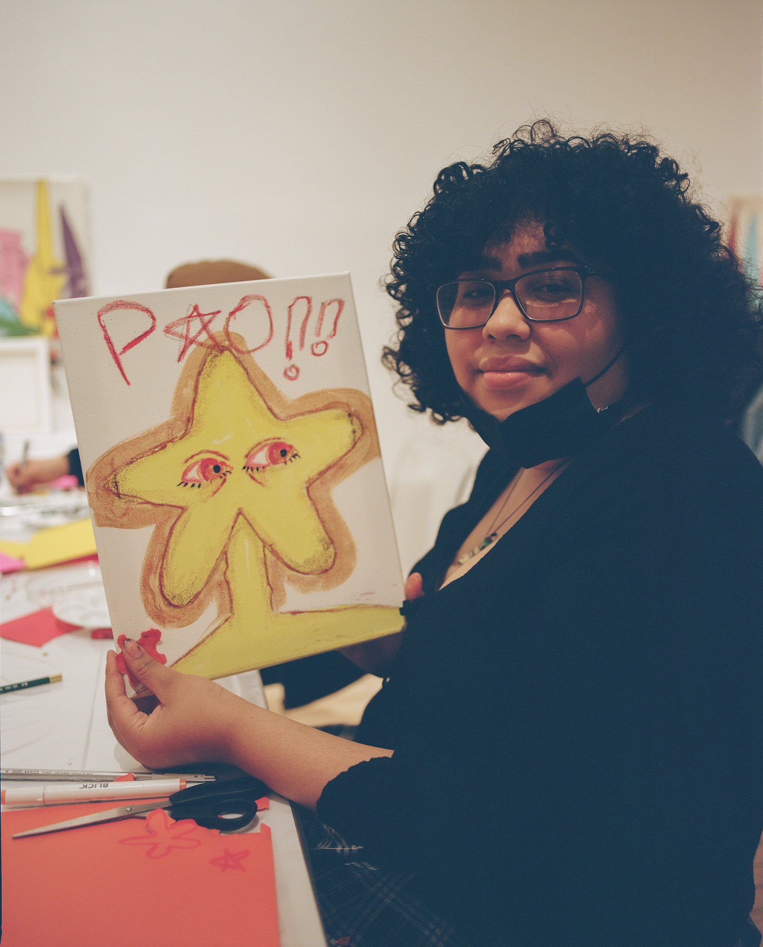 A student displays her new artwork at the Free Arts Teen Arts and Alumni Program workshop.