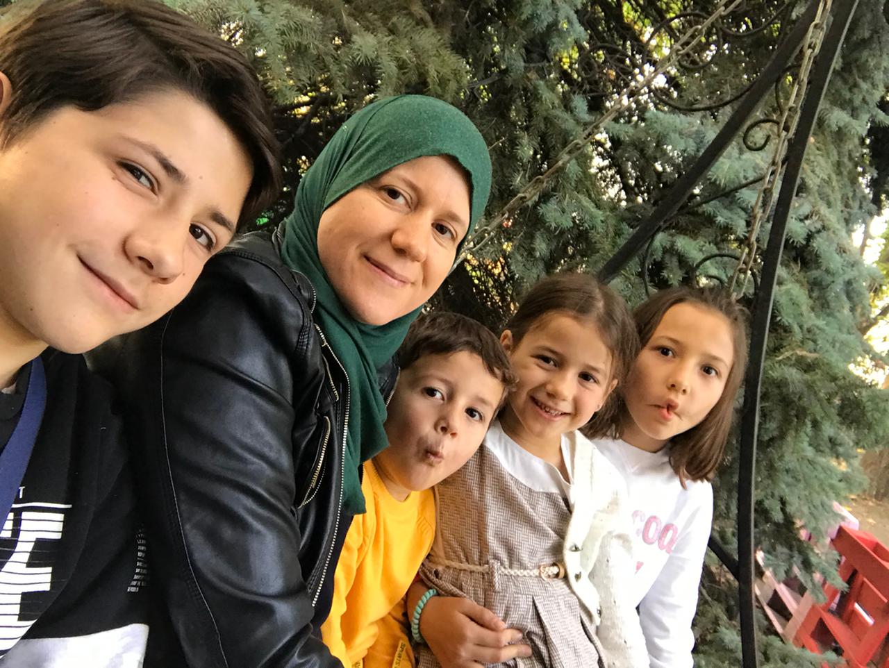 Perempuan mengenakan jilbab hijau bersama empat anak kecil