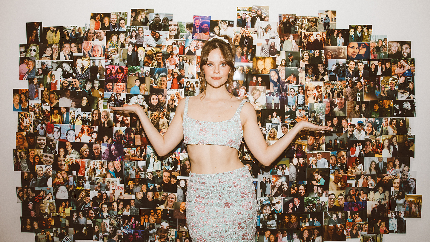 sarah ramos posa frente a una pared de fotos