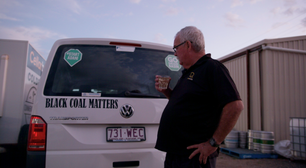 A man stands in front of his car.