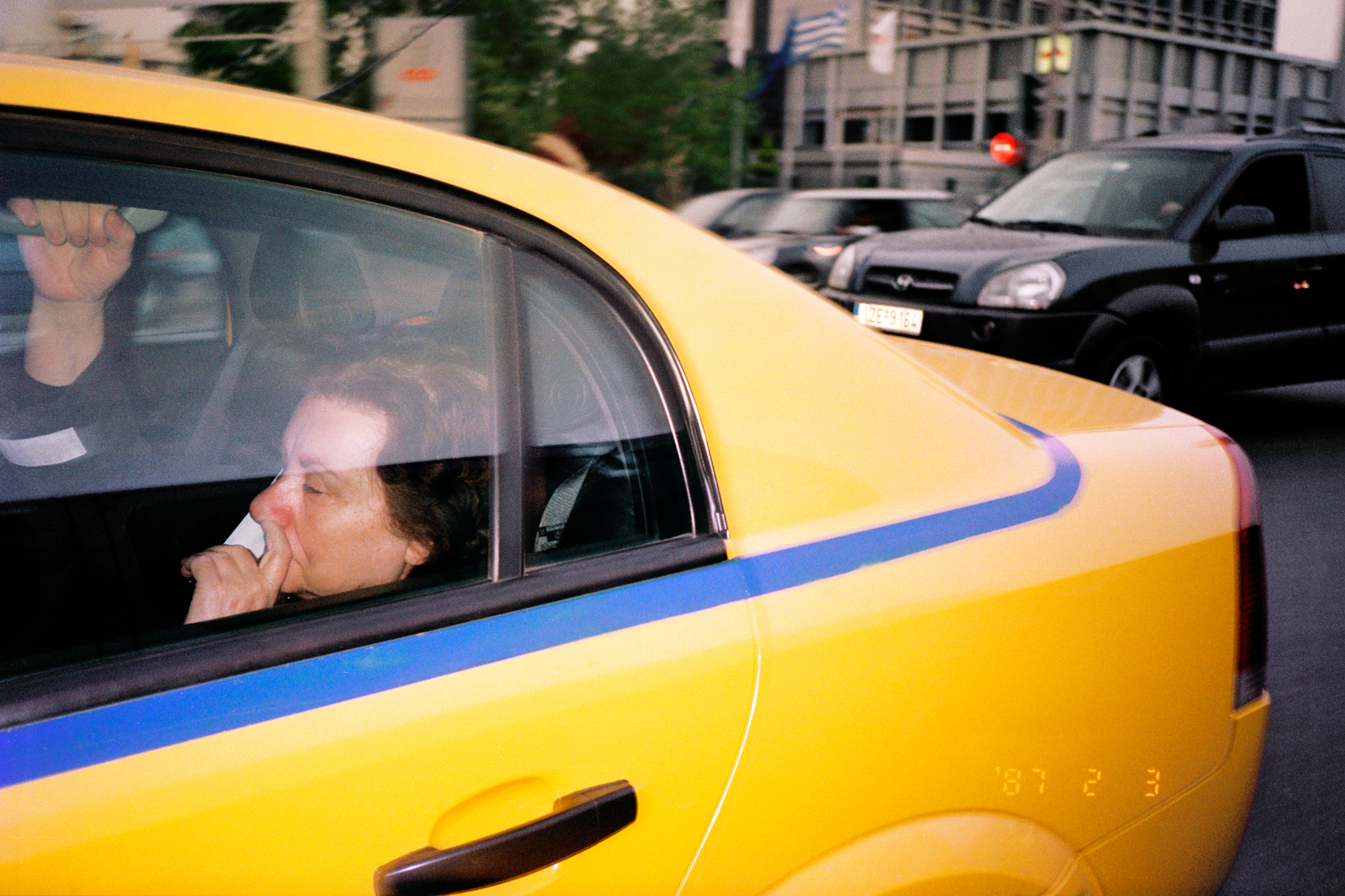 a woman holding her nose in the back of a new york city cab by jason dill