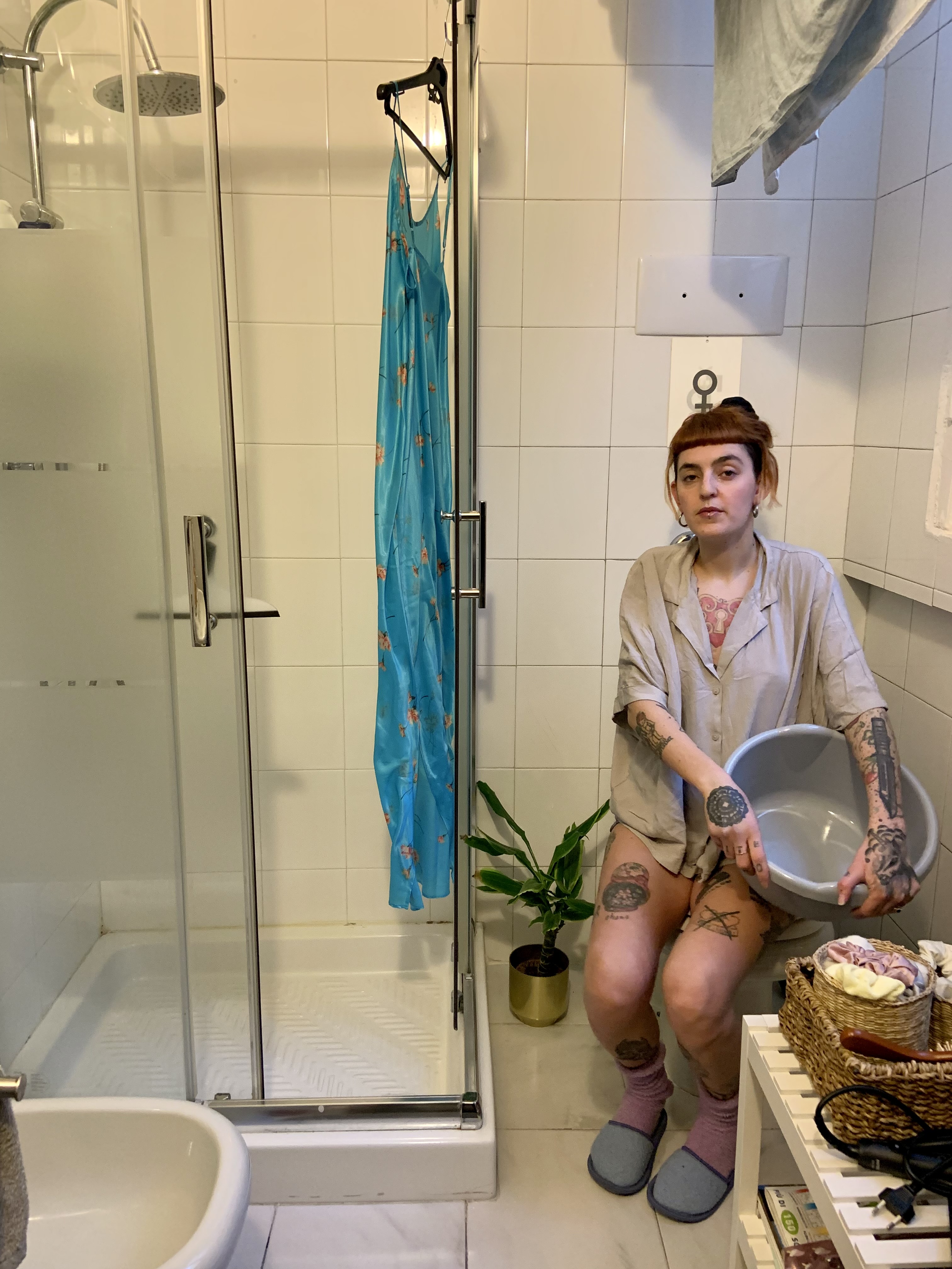 ragazza tatuata seduta in bagno con catino