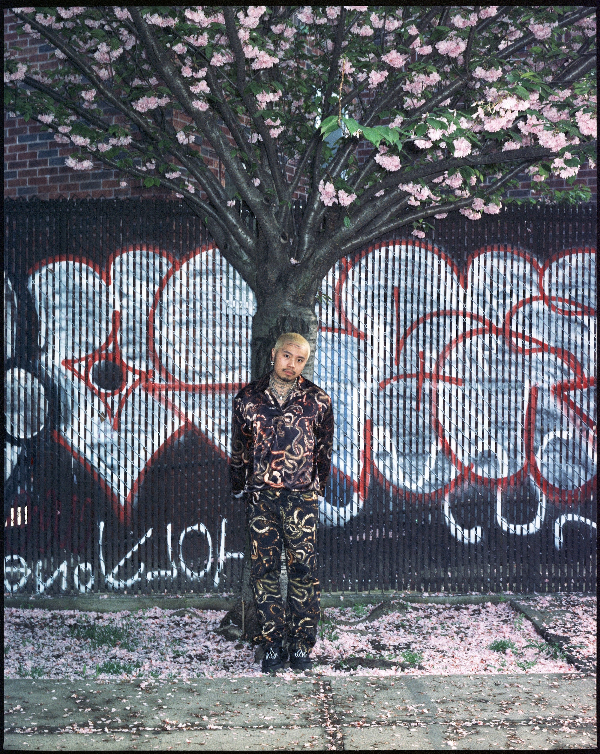 bowen goh wearing lu'u dan standing in front of a floral tree in brooklyn