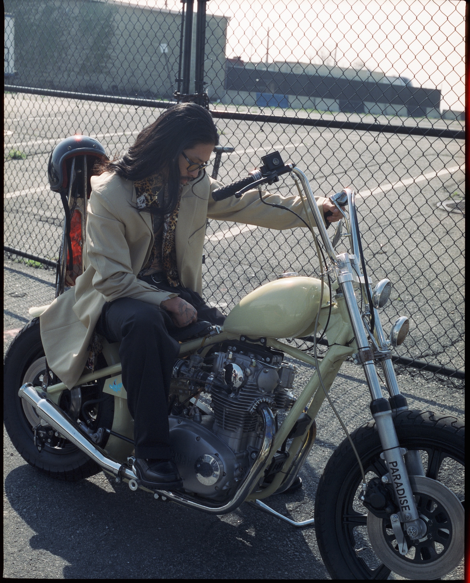 jae kim posing on a motorcycle in front of a chain link fence