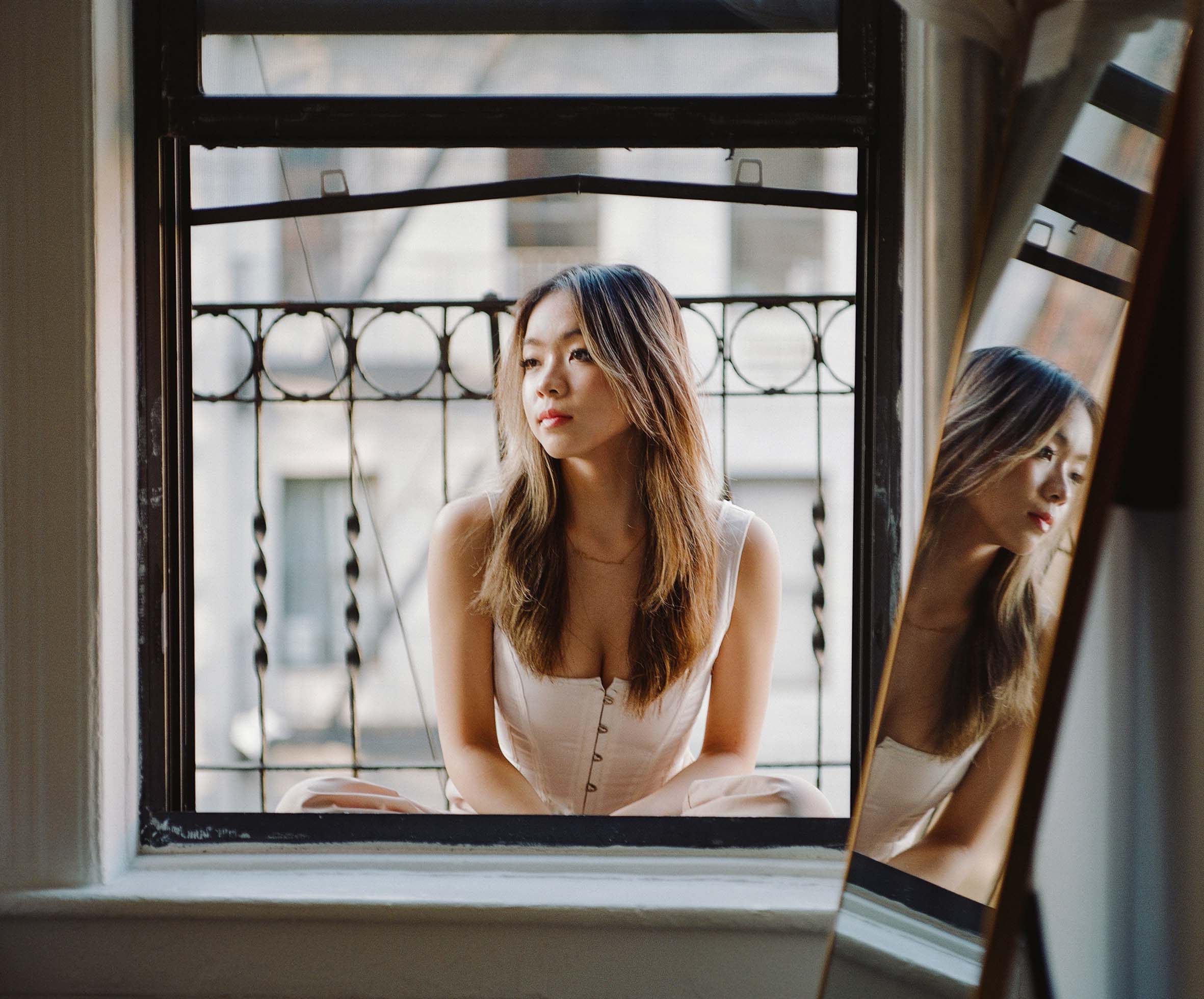 a girl in a corset sitting on her fire escape next to a mirror