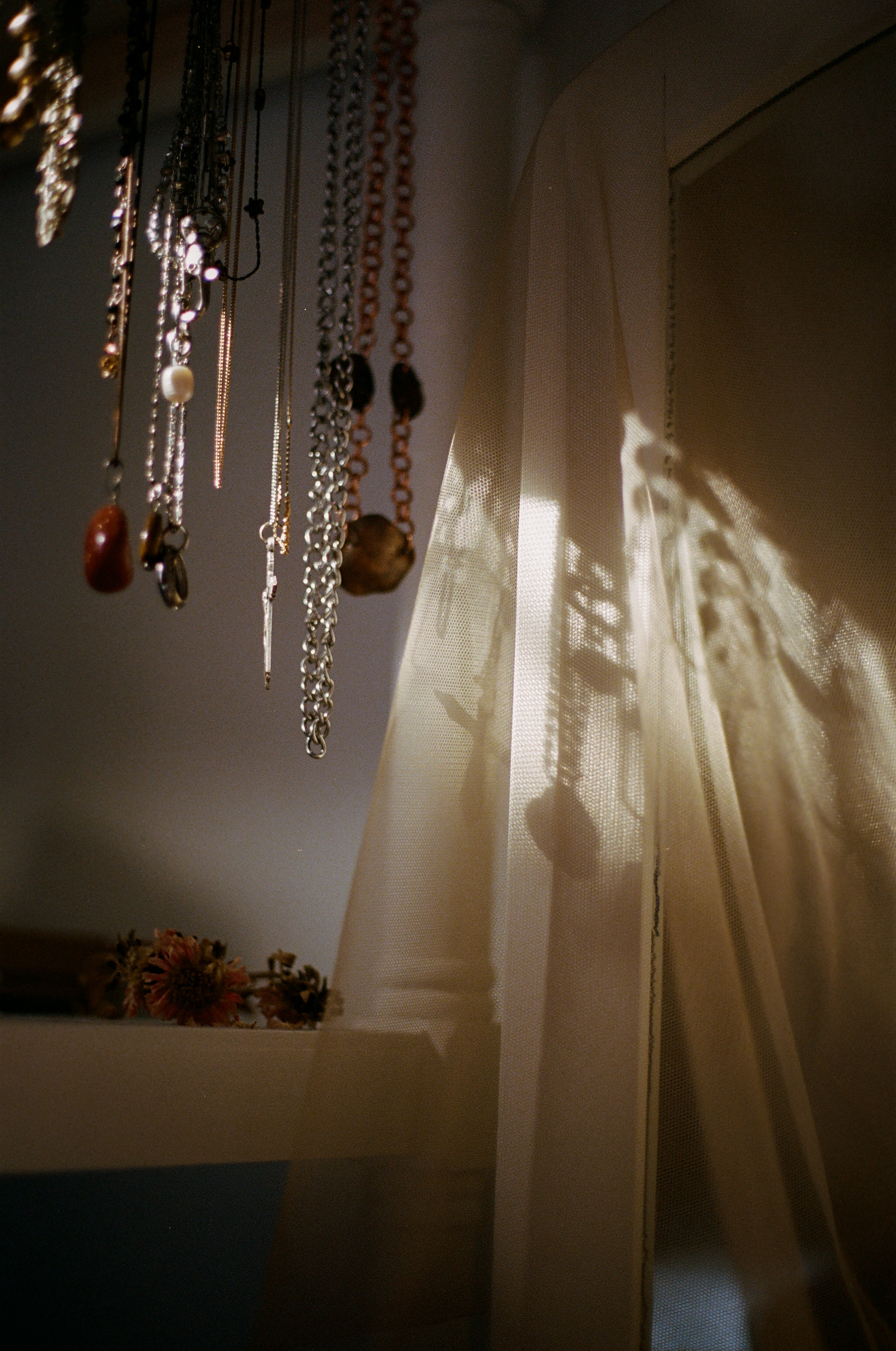 hanging necklaces and their shadows against a curtain